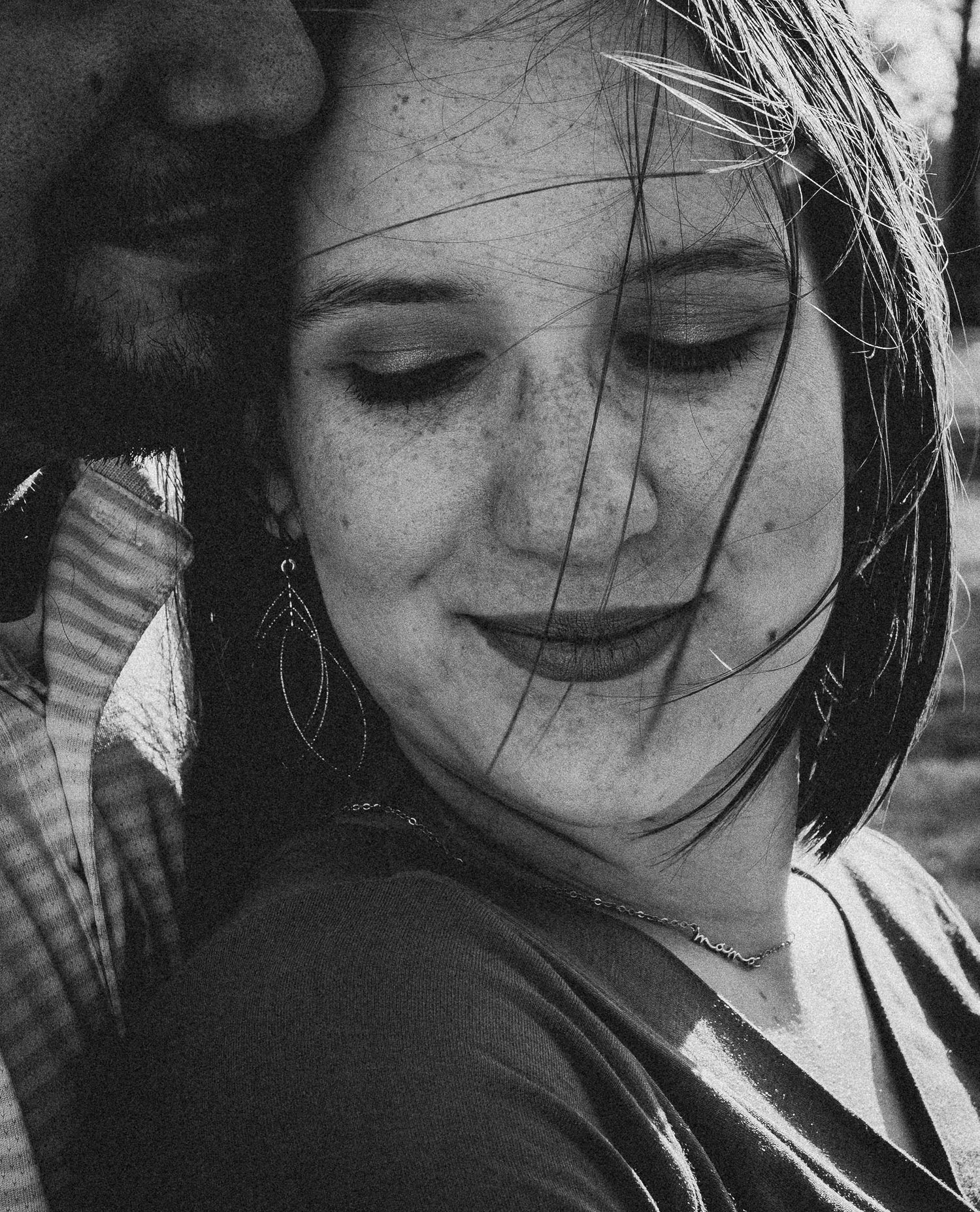 A series of black and white candid portraits showing someone smiling and looking down in different poses.