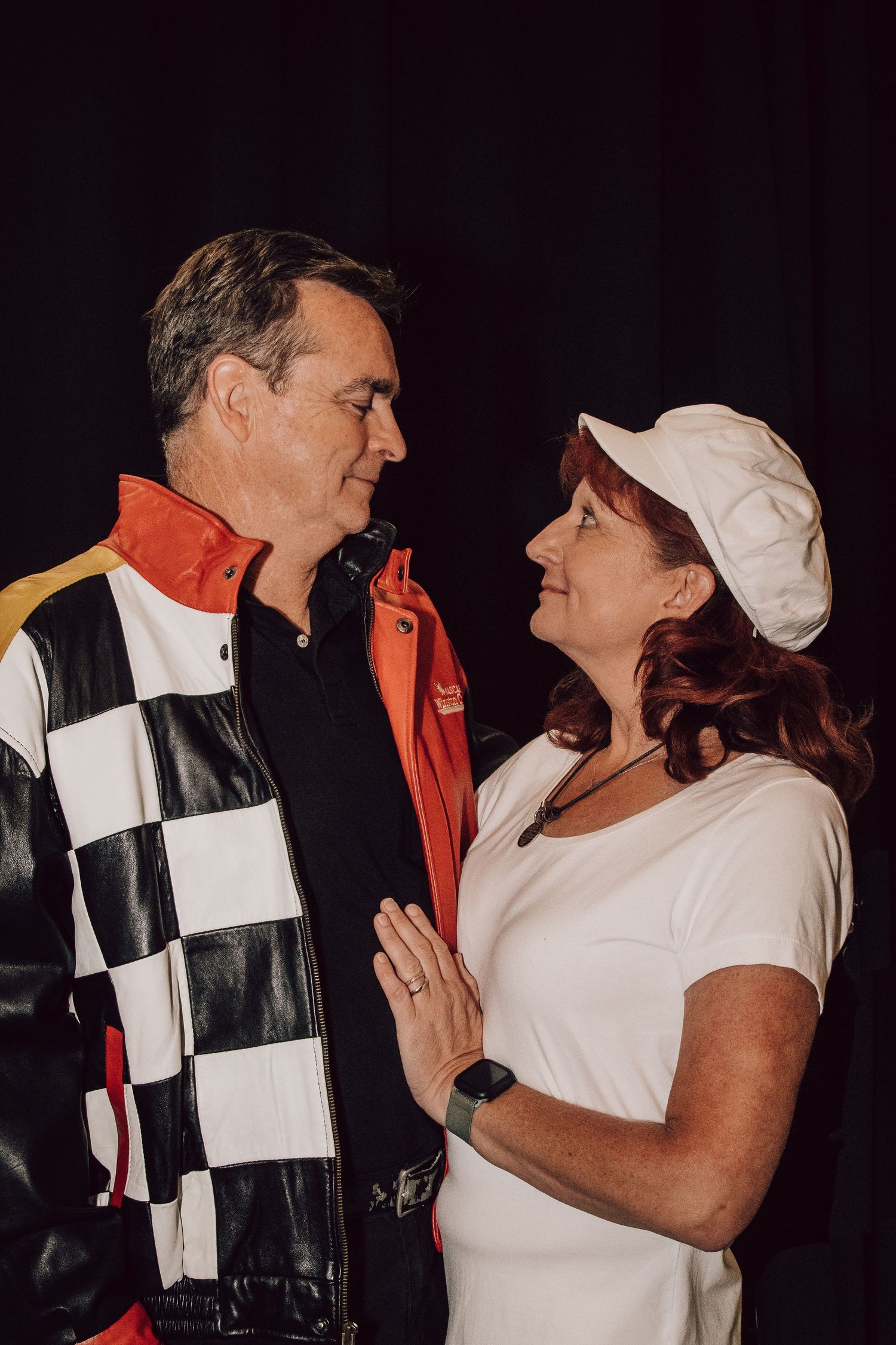 A couple shares a tender moment wearing racing-themed attire.