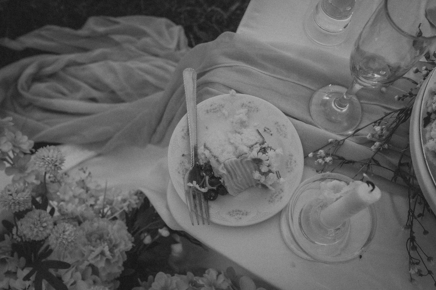 Black and white photograph of elegant table settings with wine glasses and floral arrangements at a formal dining event.