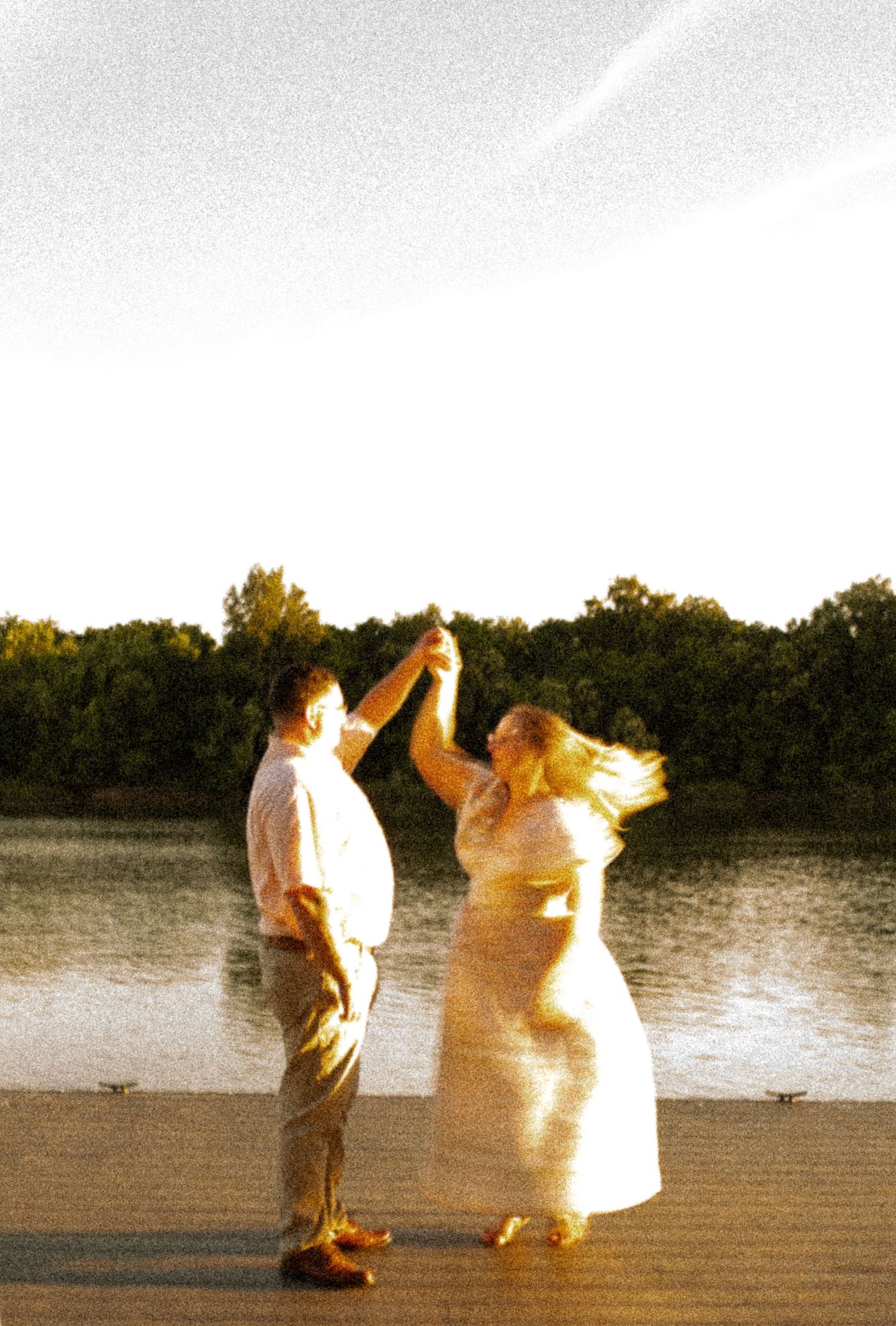 A joyful dancing scene captured at golden hour by the waterfront.