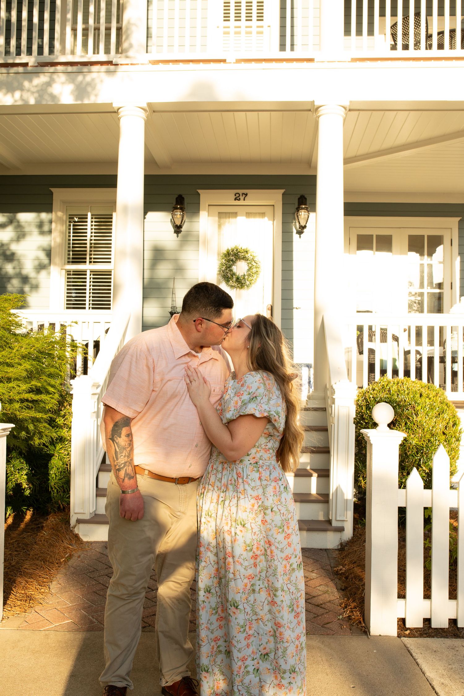 A tender moment shared on the front porch of a classic southern home with white picket fence.