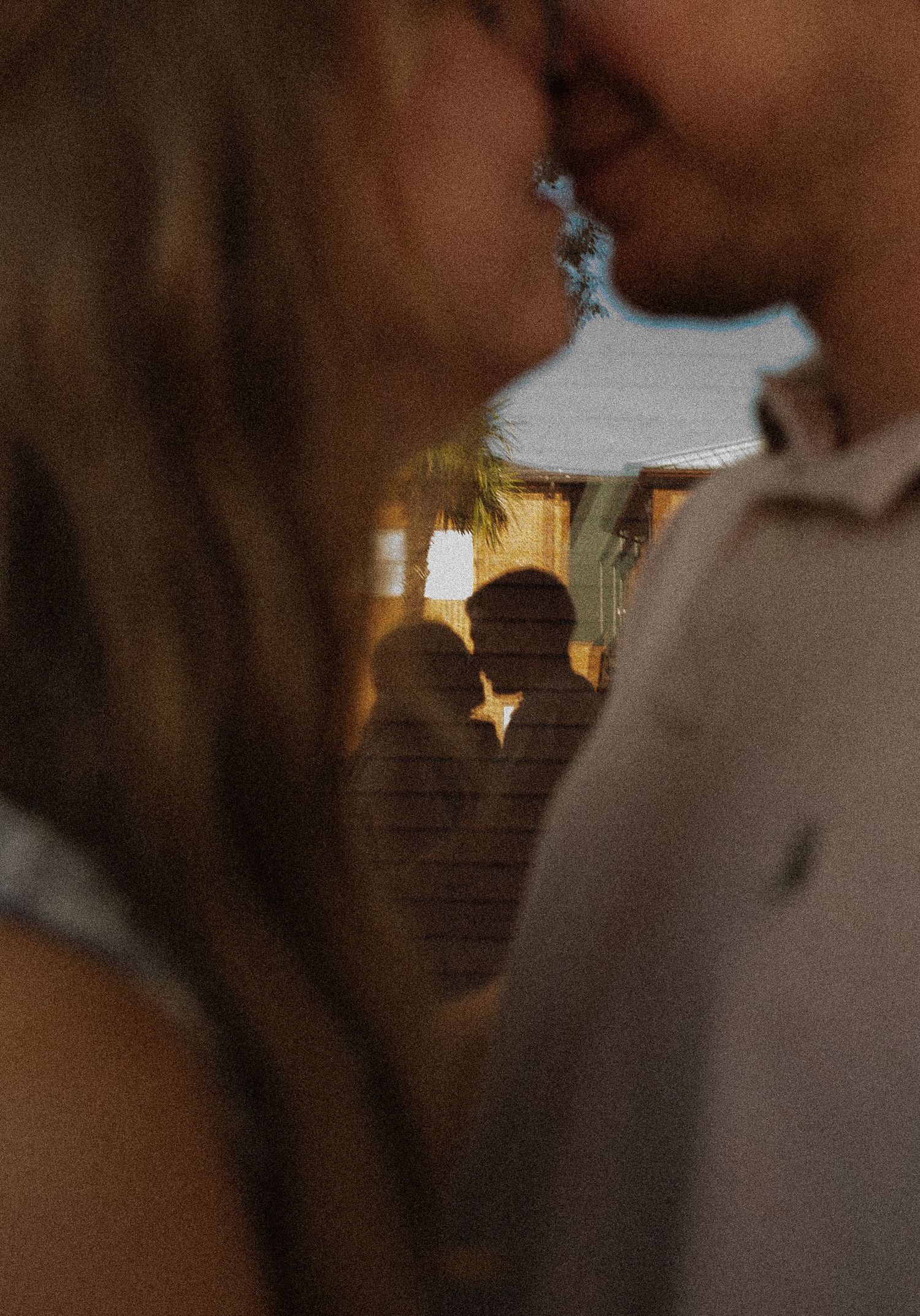 A romantic silhouette in the foreground frames a soft background view of people on stairs in warm lighting.