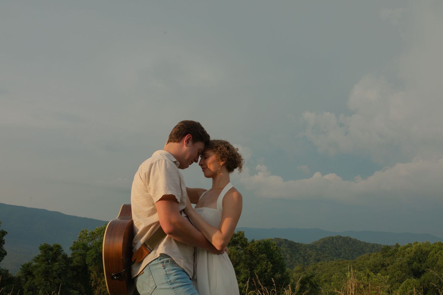 A couple embraces during their outdoor mountain wedding ceremony with scenic views of the Blue Ridge Mountains.