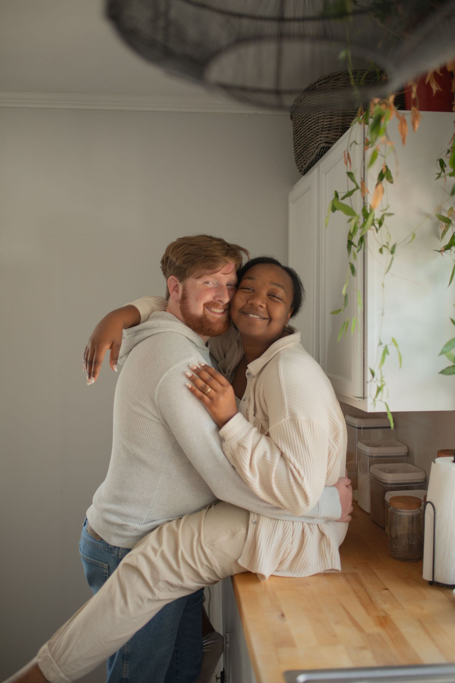 Happy interracial couple embracing and smiling together in a cozy modern kitchen at home.
