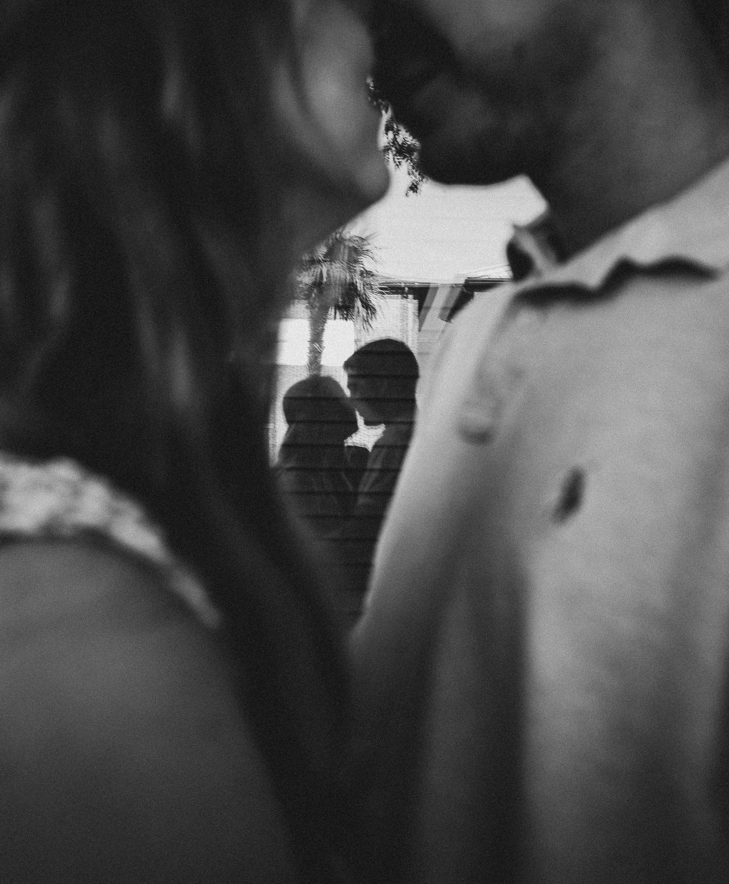 A black and white photograph shows a couple sharing an intimate kiss in a romantic moment.