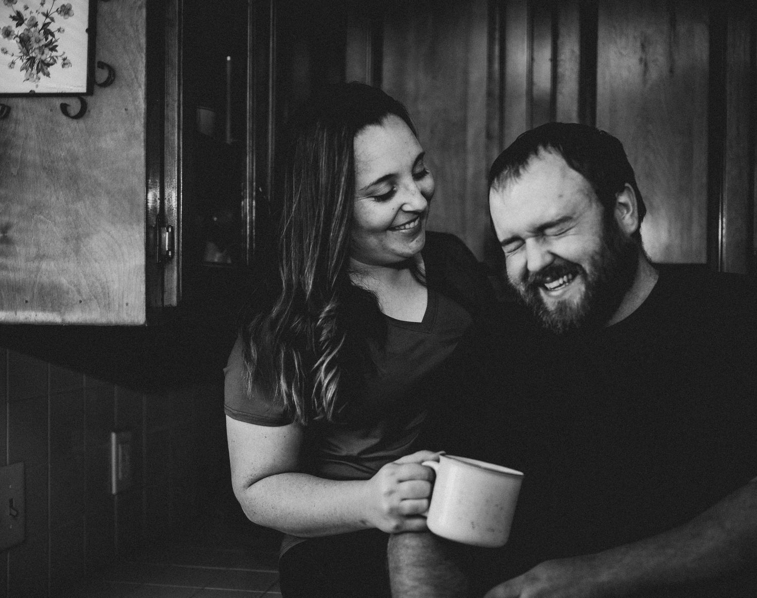 Cozy black and white photo of a couple sharing coffee and laughter.
