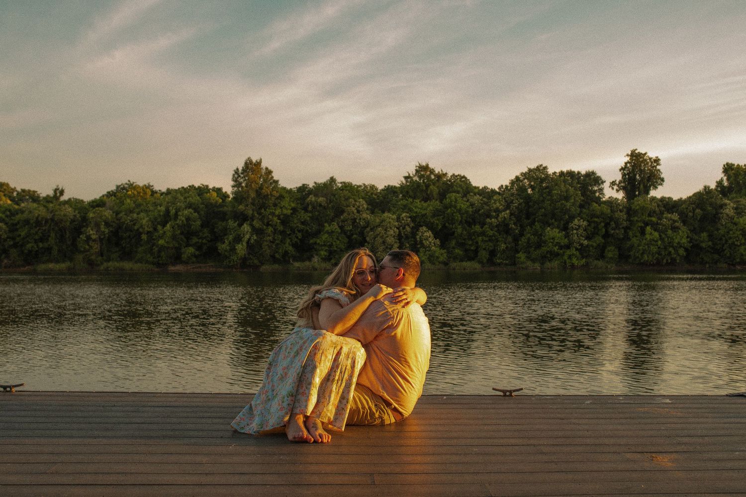 A romantic sunset scene on a wooden dock overlooking a tranquil lake.
