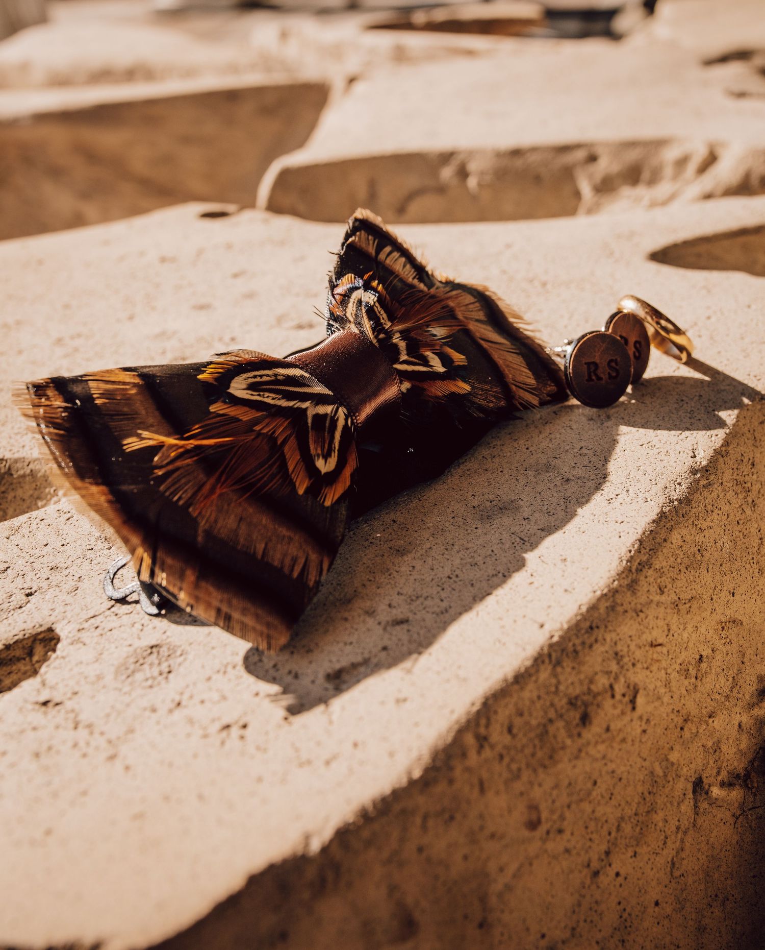 A brown and black patterned bandana lies on rough beige concrete steps in warm sunlight.