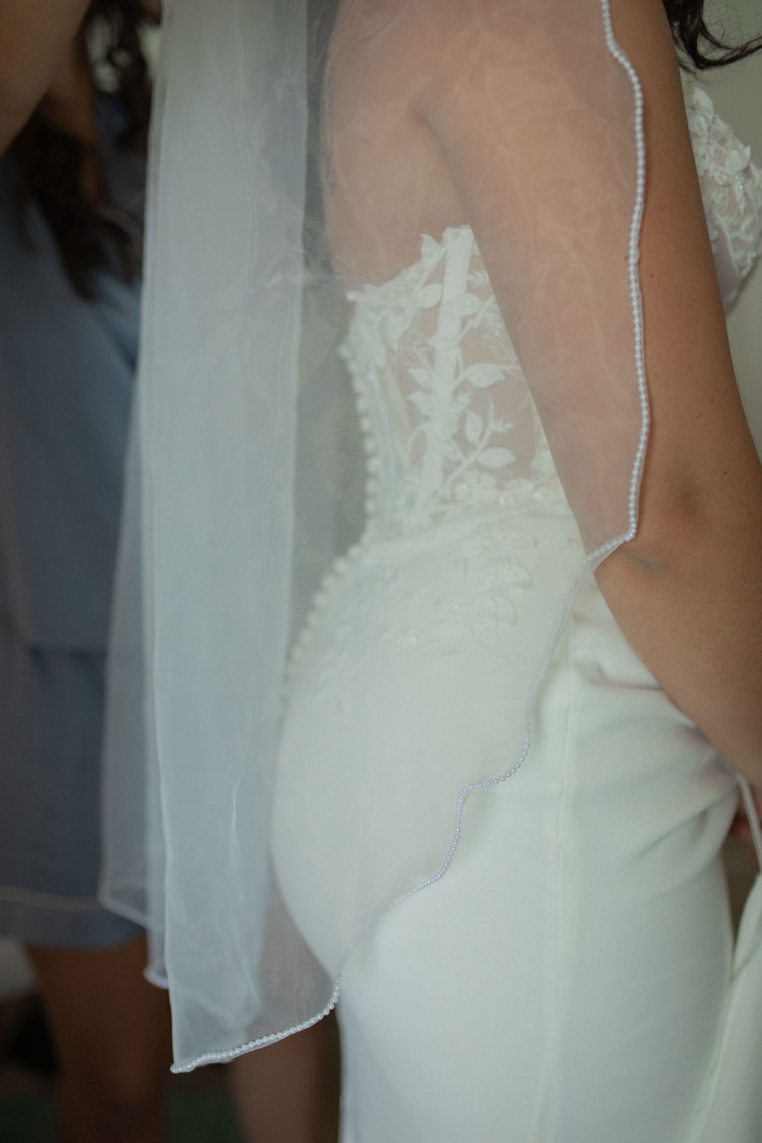 Close-up of a bride in a white lace bodice wedding gown with a sheer veil, showcasing elegant bridal fashion details.