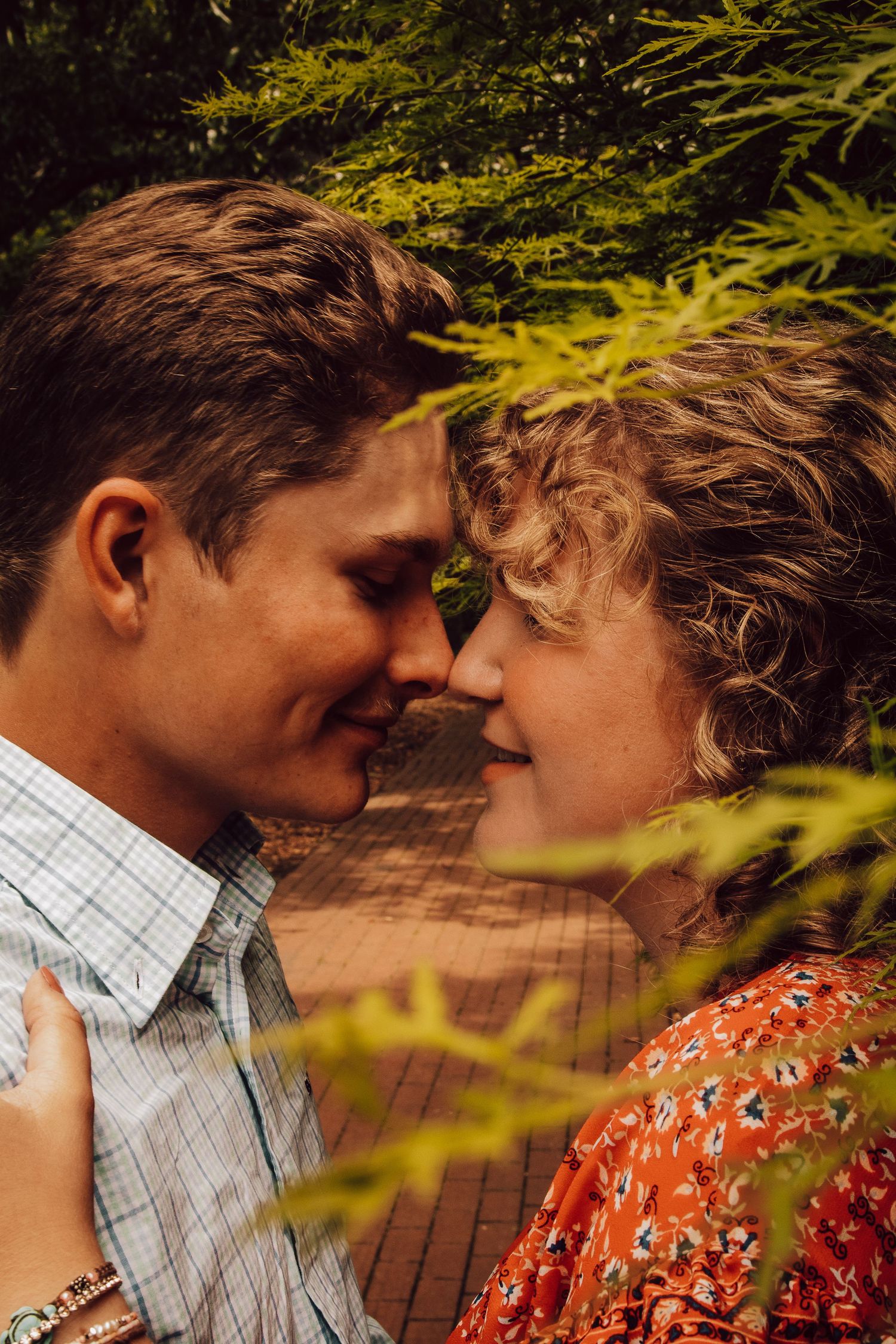 Intimate close-up of a couple sharing a tender moment among green foliage.