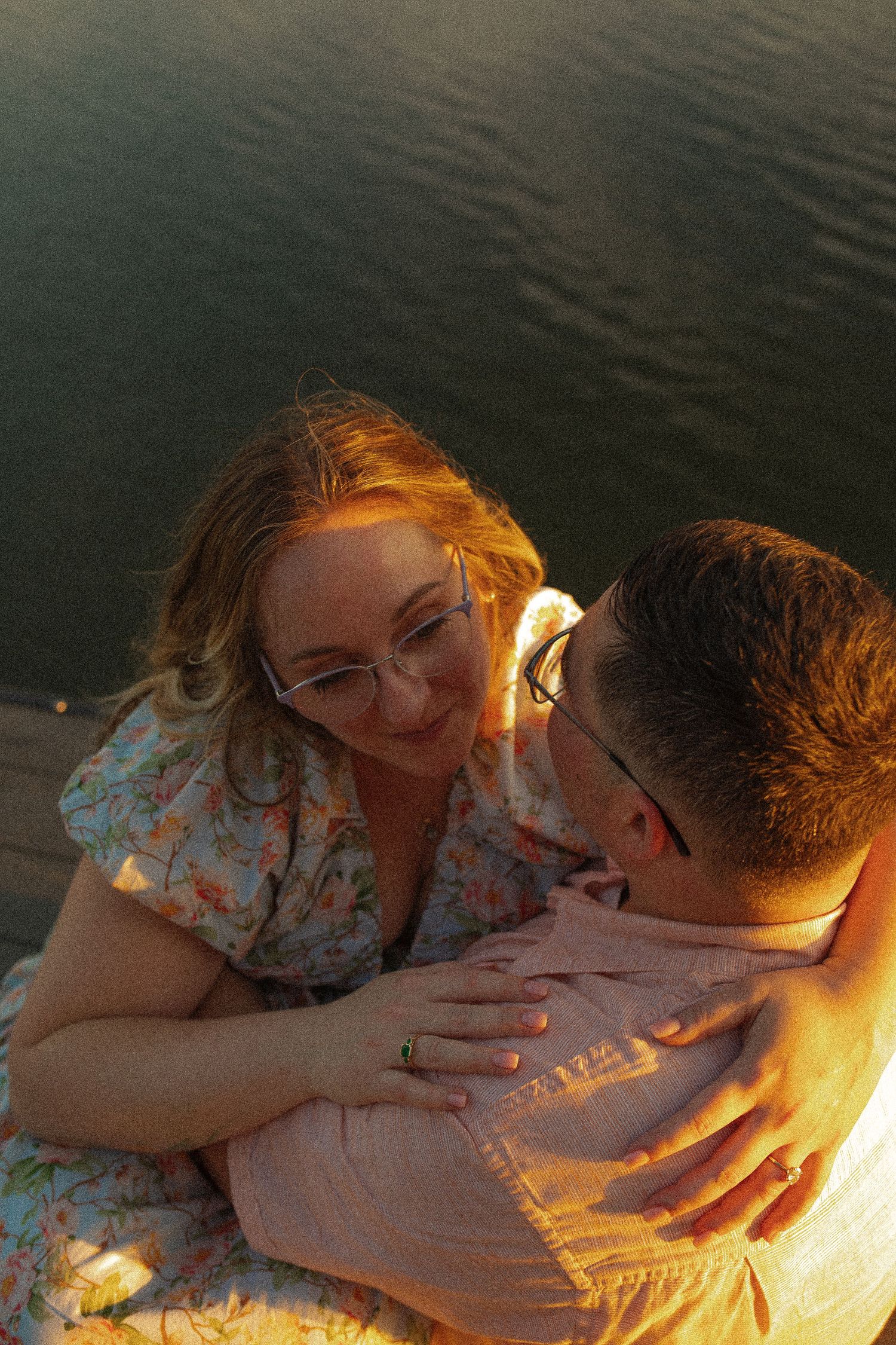 A tender moment between a couple lit by golden hour sunlight on a dock.