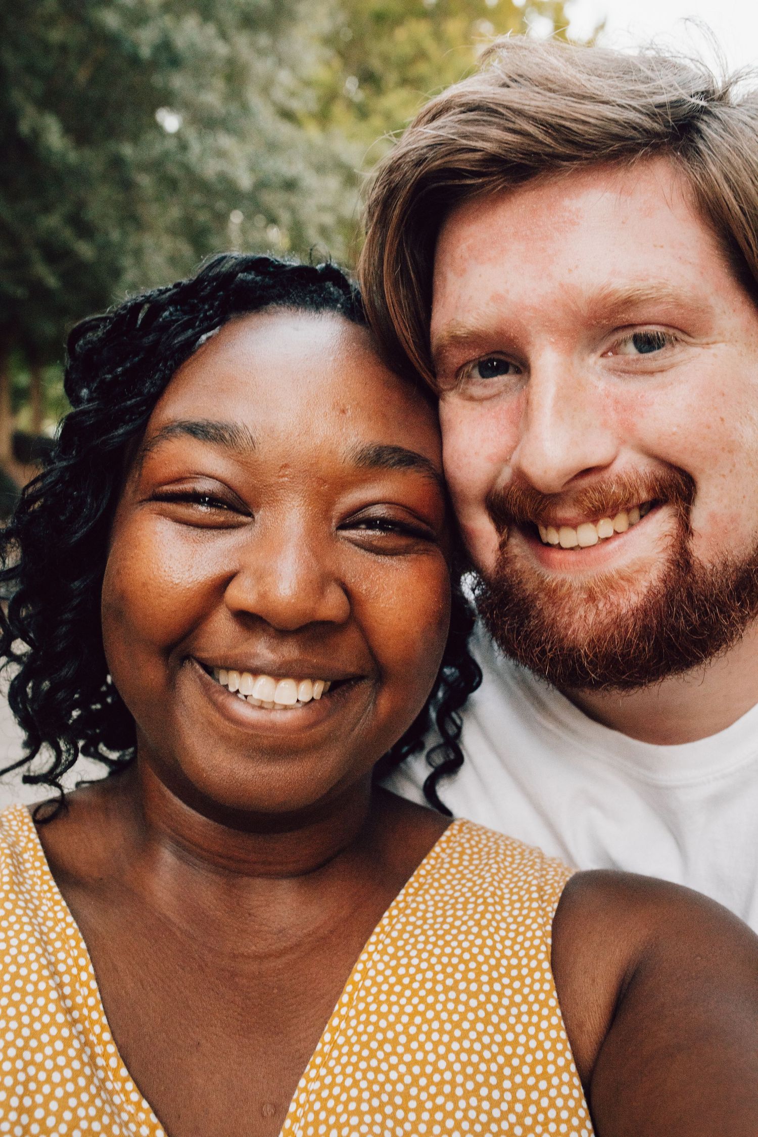 A happy couple taking a selfie outdoors while wearing casual summer attire.