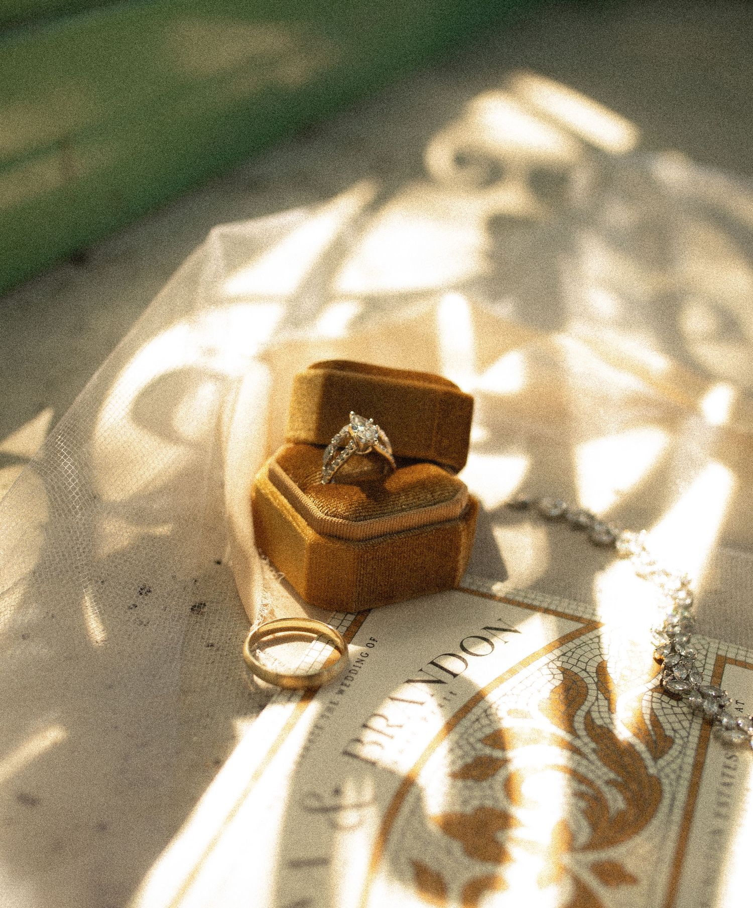Diamond engagement ring in wooden box casting delicate shadows on a white surface in soft natural light.