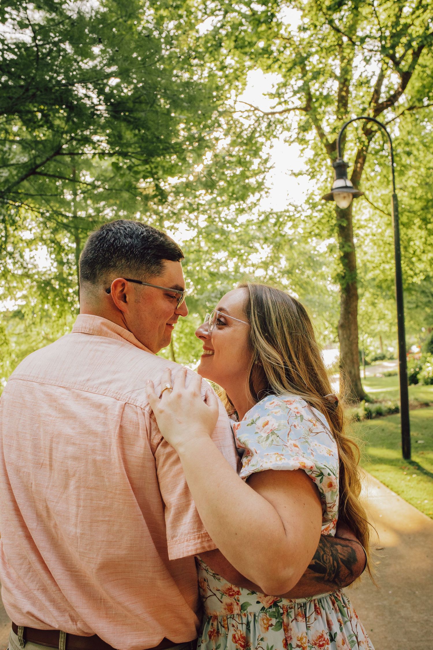 Couple laughing together outdoors in sunny park setting.