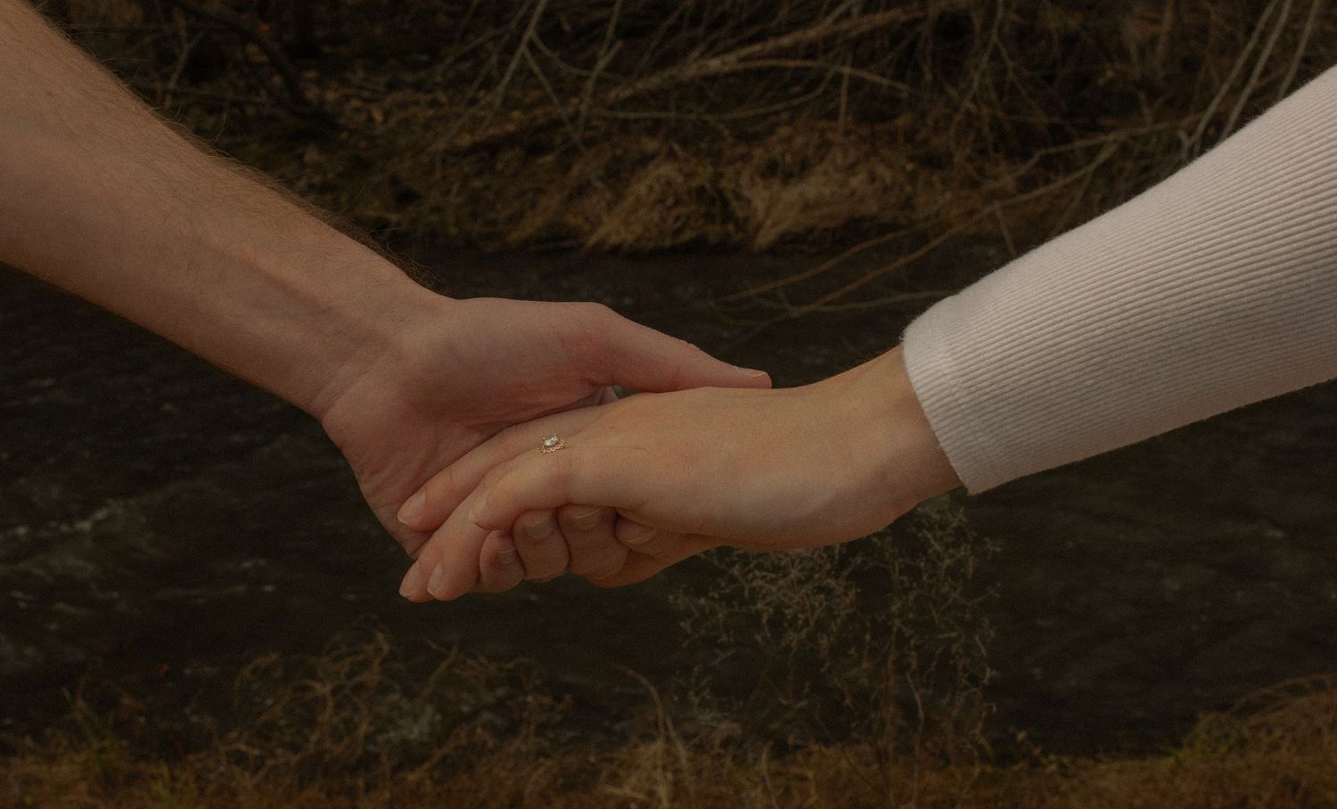 Two hands reaching towards each other against a dark background in a romantic gesture.