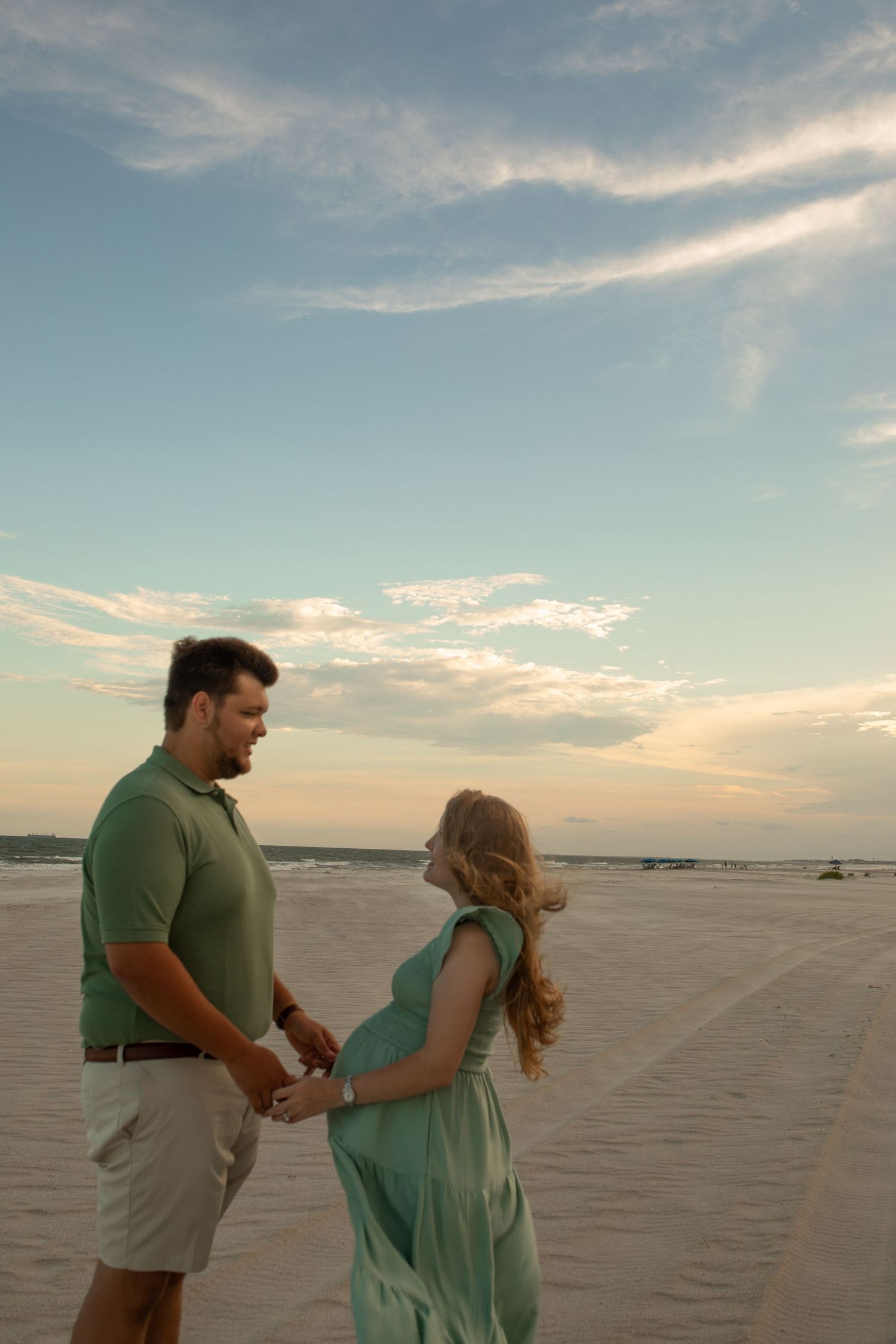 A couple shares an intimate moment on an empty beach during sunset.
