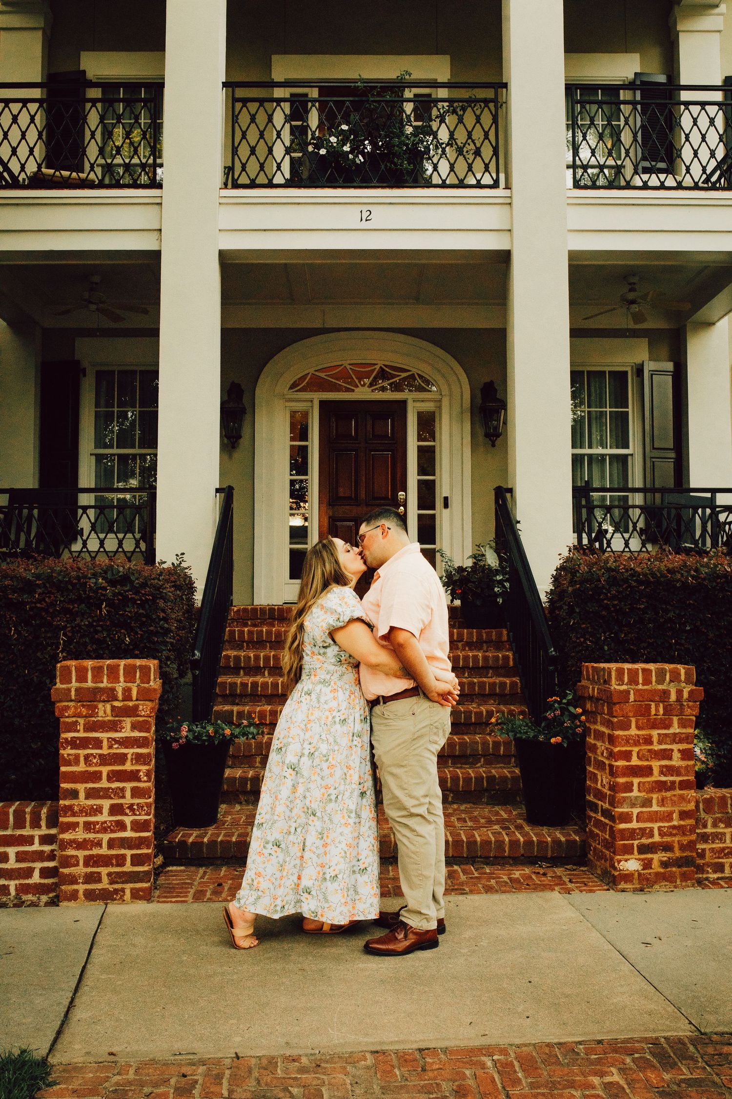 A romantic moment on the steps of a grand southern colonial home with white columns and brick accents.