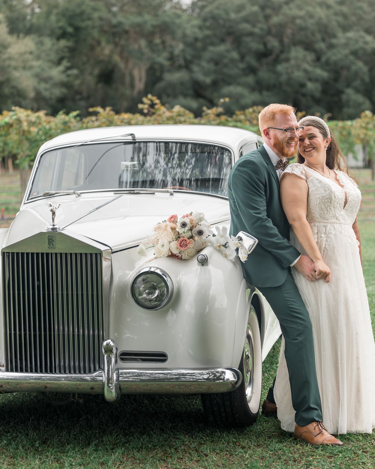 Classic white Rolls Royce luxury car decorated with flowers for an elegant outdoor wedding celebration.
