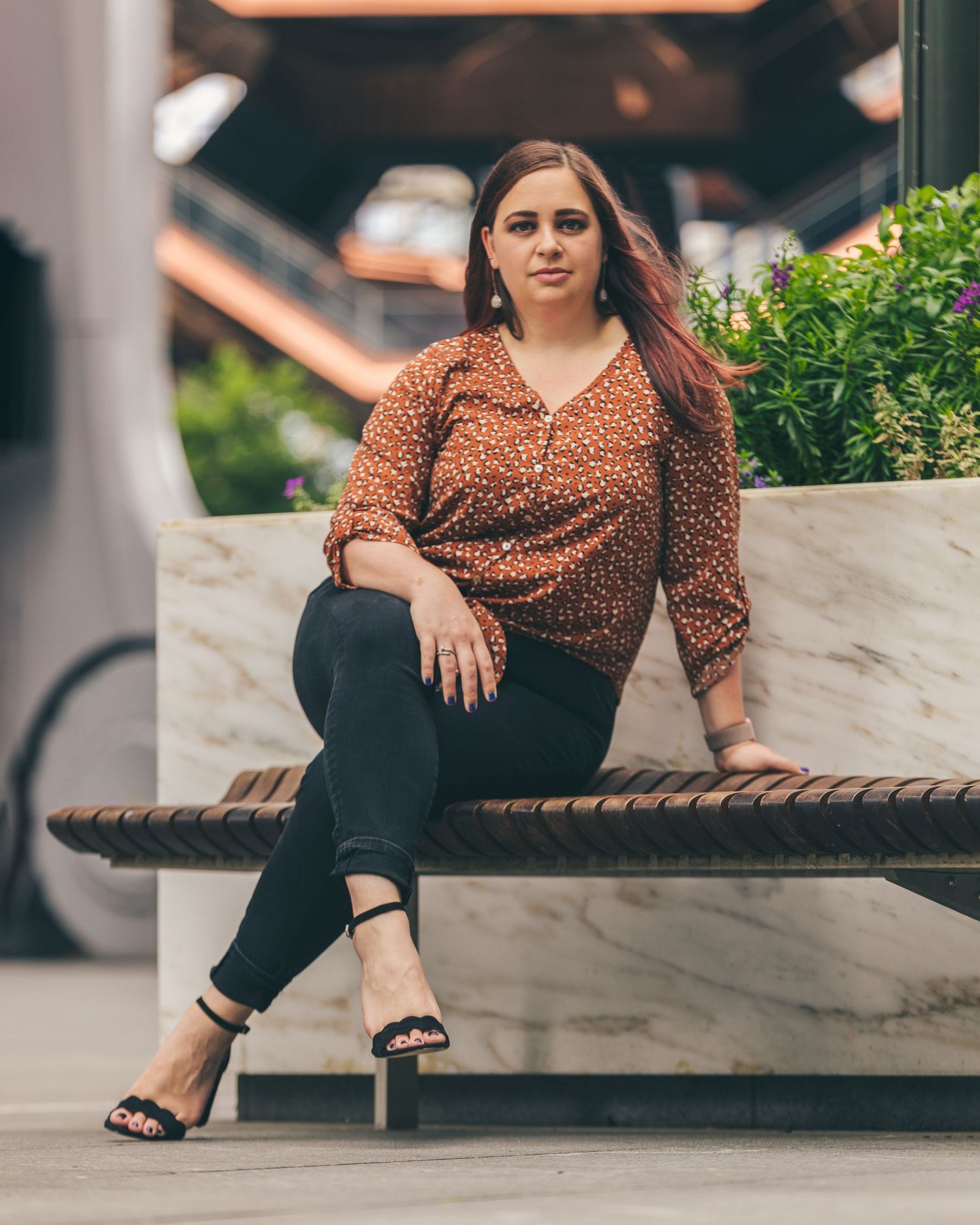 Woman in leopard print top relaxing on modern marble bench outdoors.