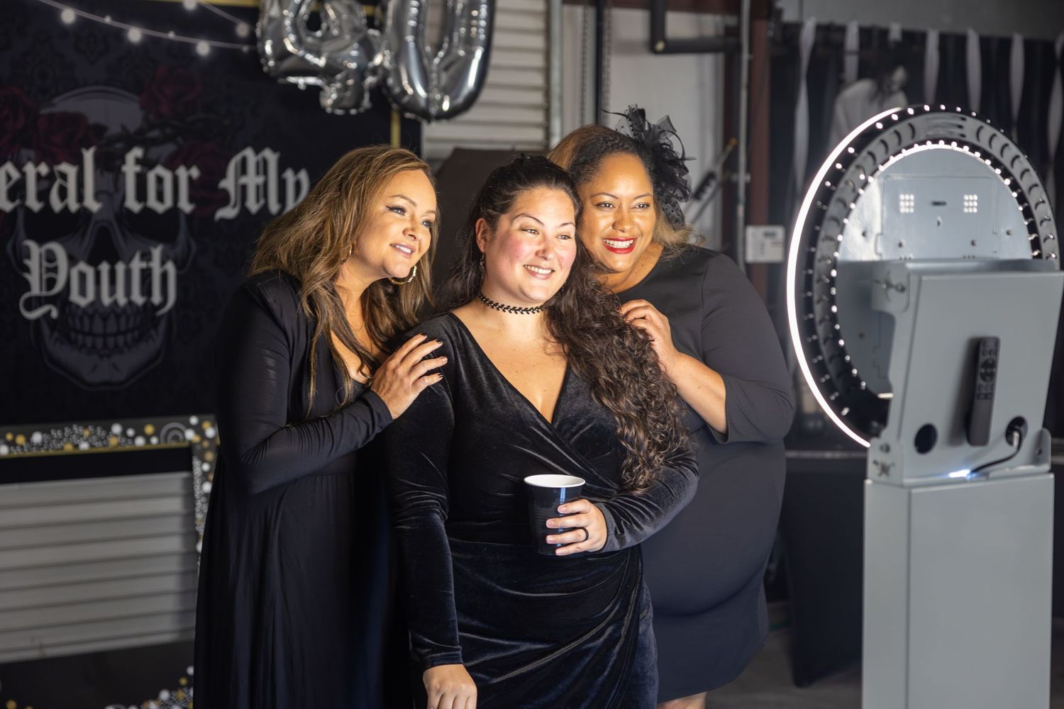 Three women smiling in front of photo booth