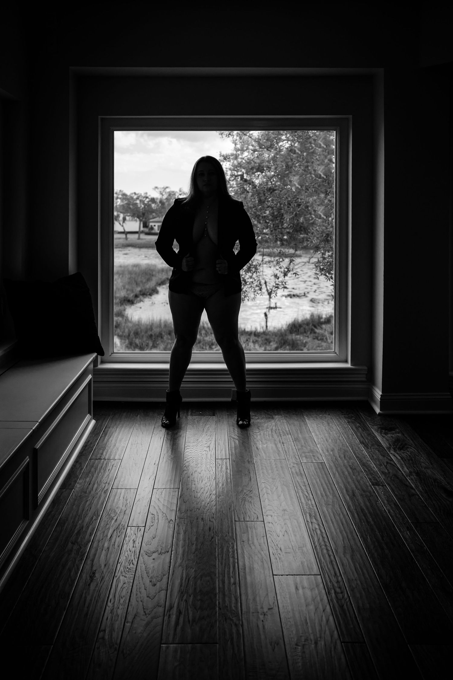 Dramatic silhouette by window with hardwood floors and natural light.