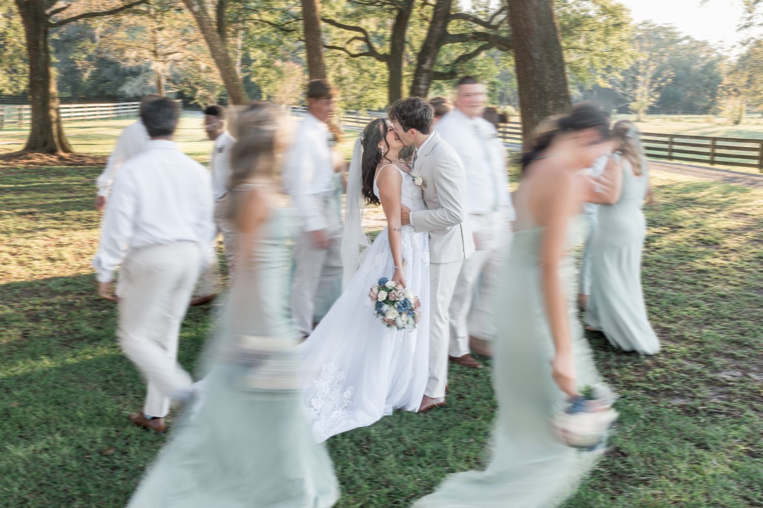 Wedding party celebrating outdoors in white attire with natural lighting.