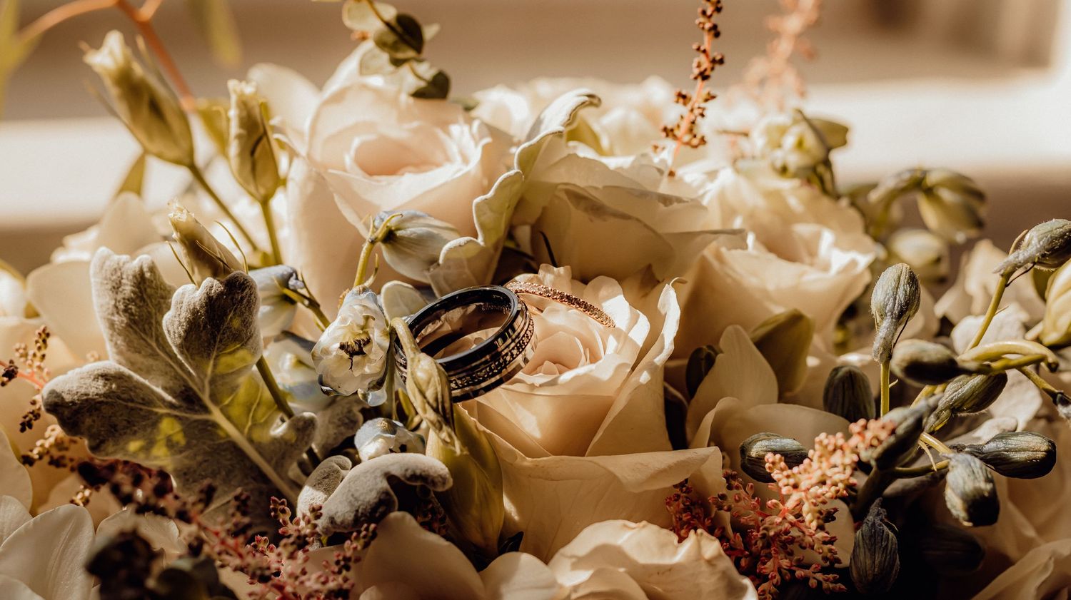 Delicate roses and small white flowers create a romantic floral arrangement in soft natural lighting.