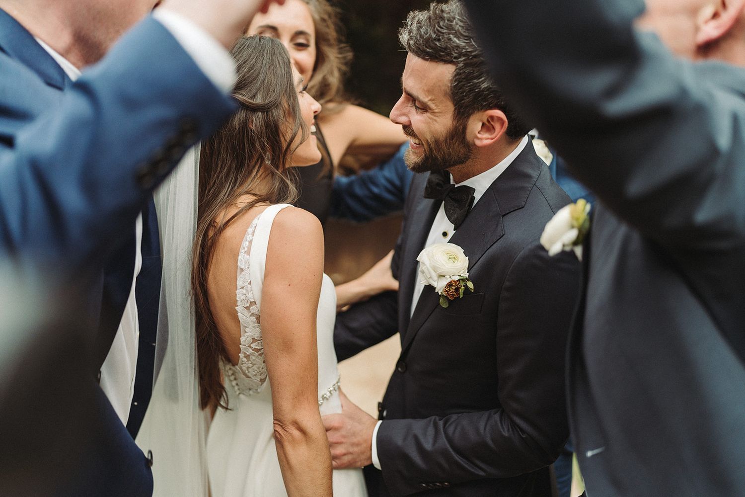 Couple shares a tender moment together at their wedding, wearing white gown and black suit with boutonniere.
