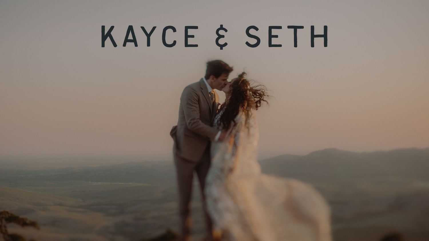 Kayce and Seth share a romantic kiss on a mountain overlook at sunset in their wedding attire.