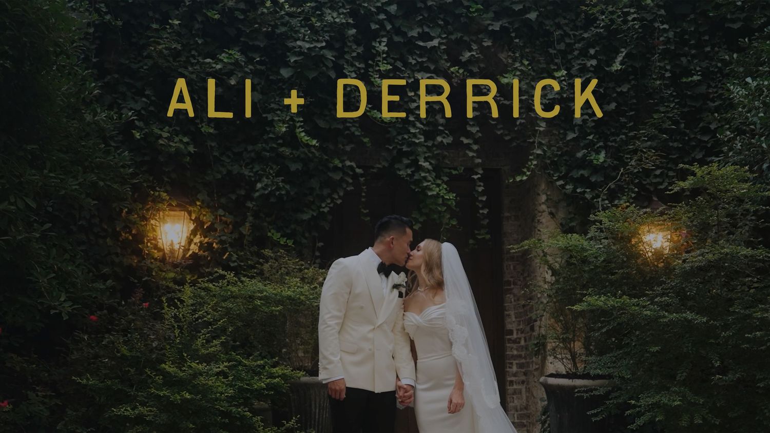 Ali and Derrick share a romantic wedding kiss surrounded by lush greenery and warm golden lights.