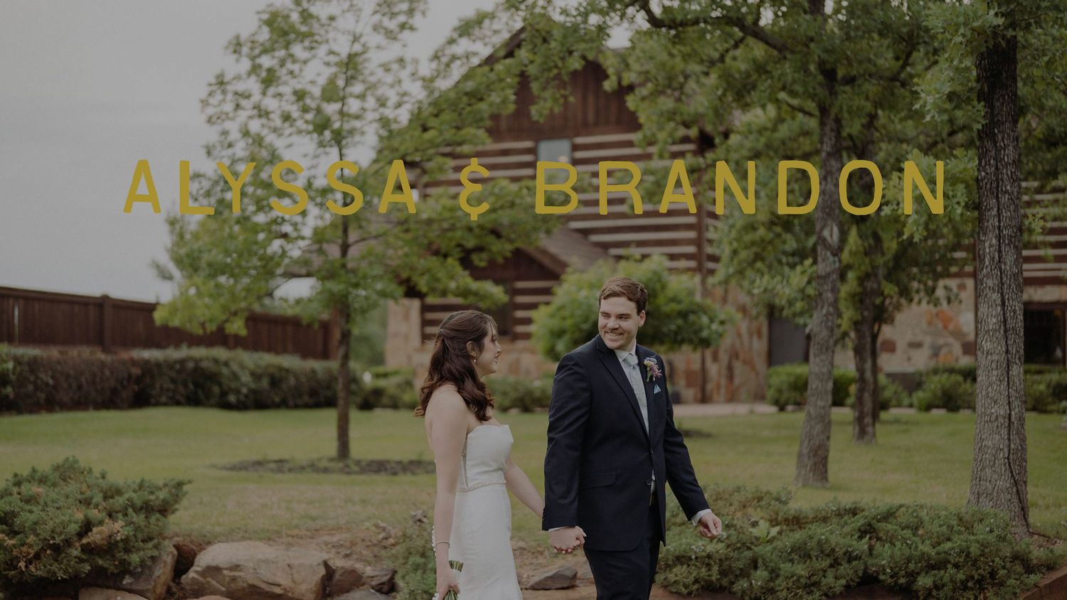 Alyssa and Brandon wedding video thumbnail featuring couple in formal attire standing on green lawn near rustic log cabin venue.