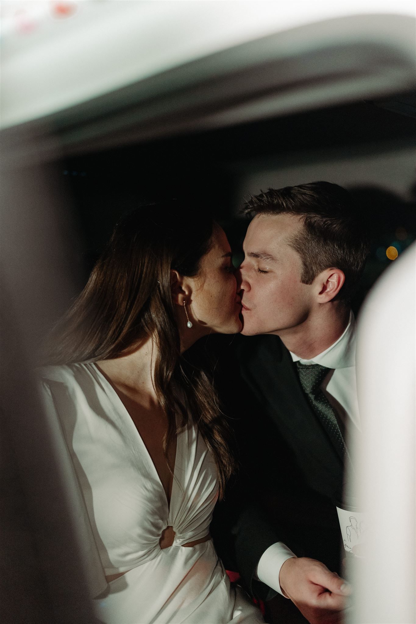 A romantic couple shares an intimate kiss while dressed in formal wedding attire on their special day.