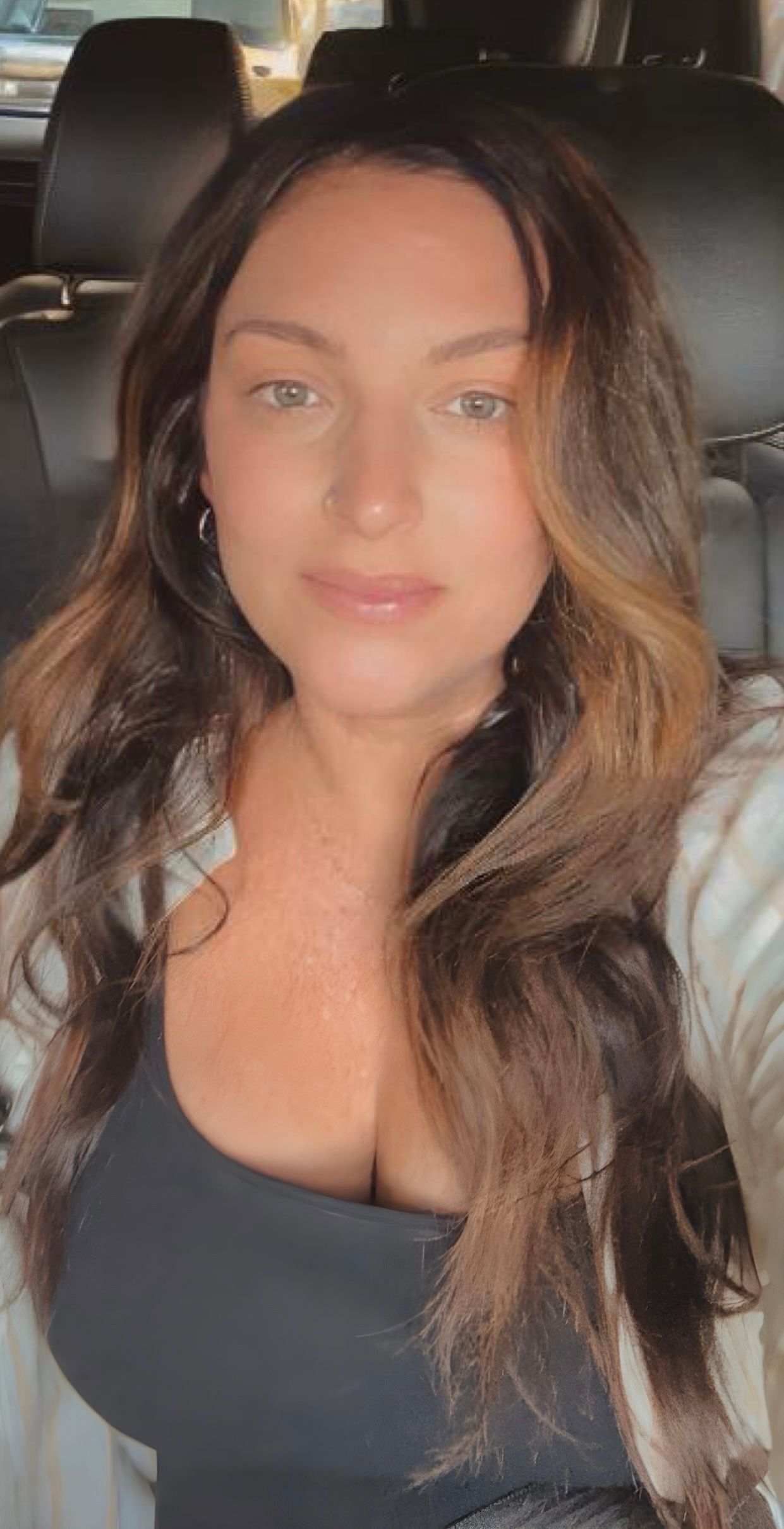 A series of selfies showing someone with long wavy brown hair wearing a black top in a car.