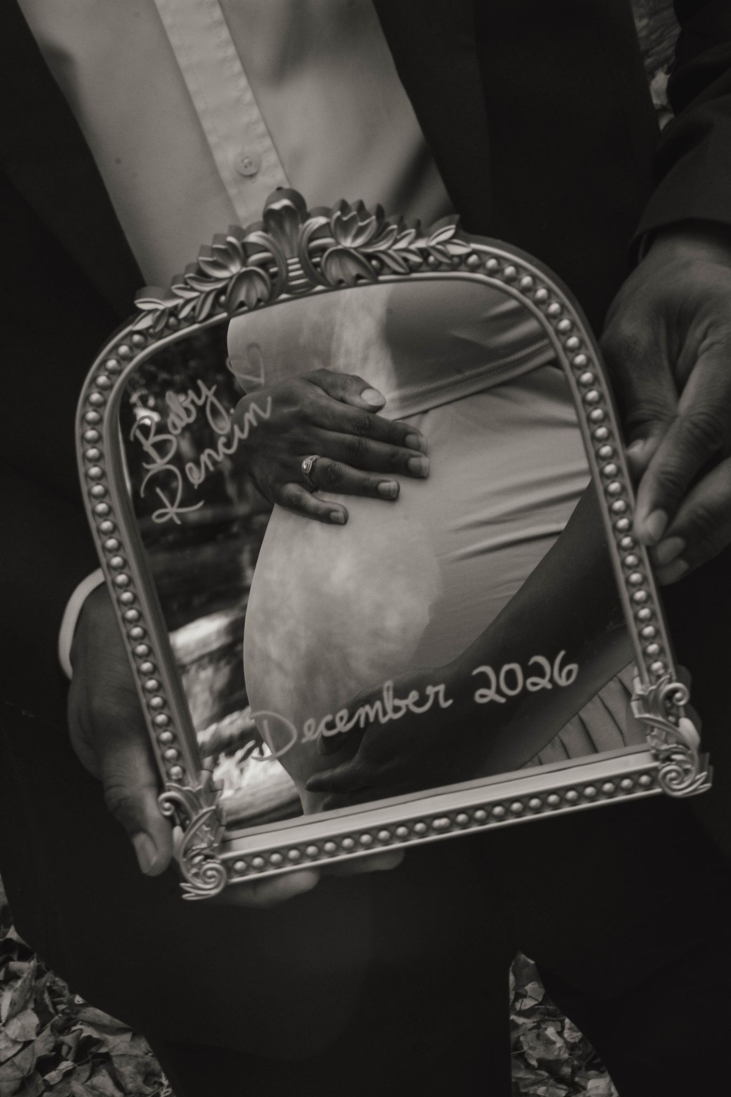 Black and white photo of a vintage mirror reflecting an expecting mother's belly with a baby name and December 2026 due date.