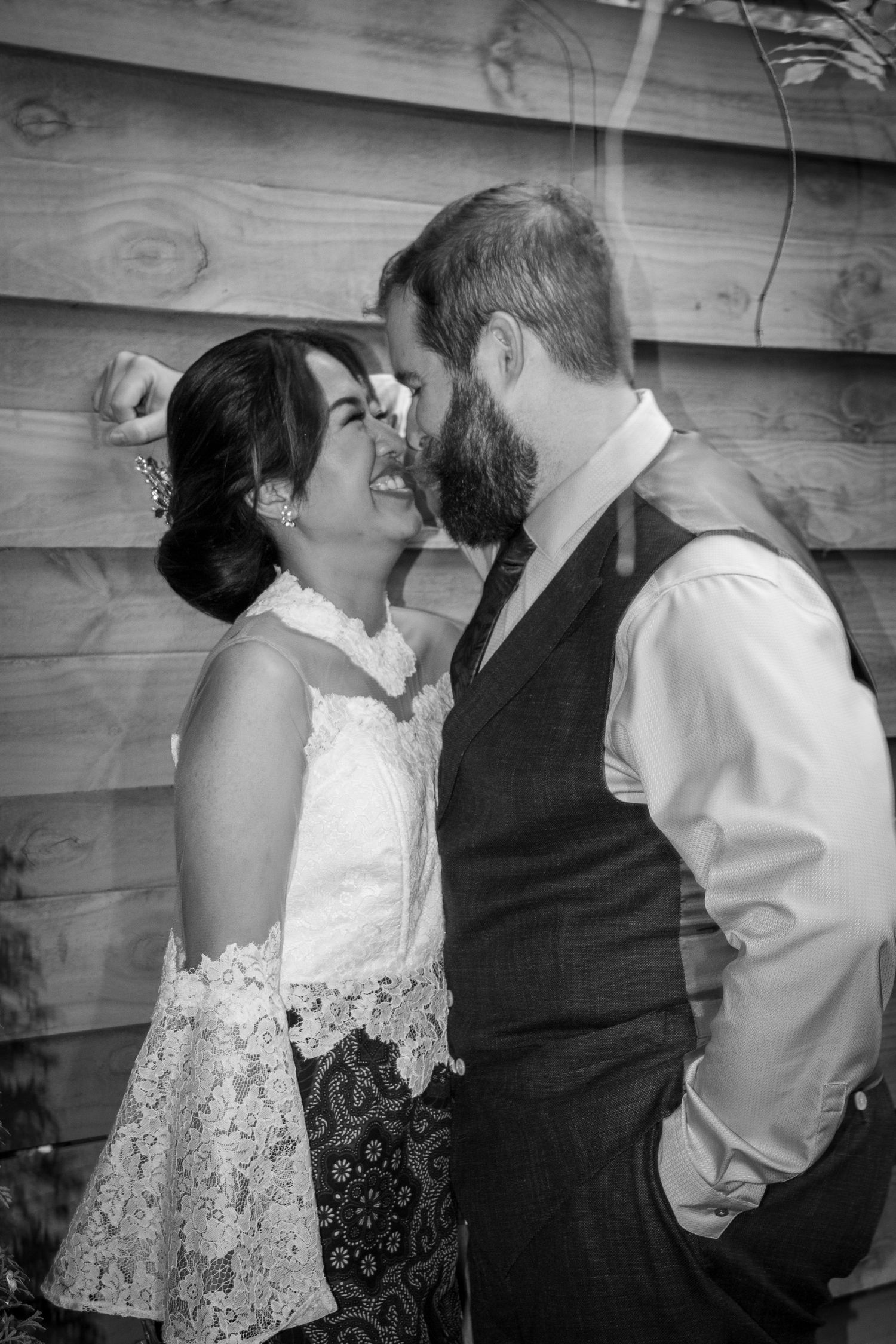 Black and white photo of laughing bride and bearded groom sharing intimate moment.
