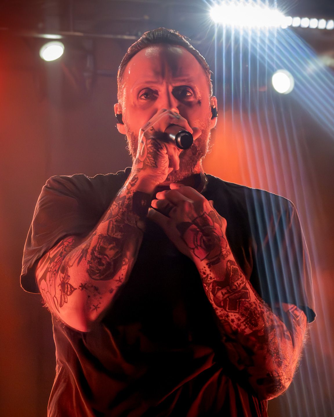 Justin Furstenfeld of Blue October performing live under dramatic red stage lighting at Moody Amphitheater in Austin, Texas.