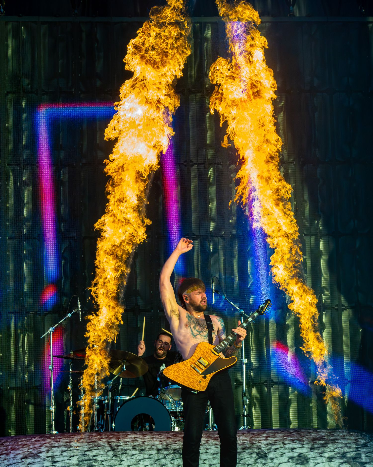 Beartooth Caleb Shomo performing on stage surrounded by dramatic fire and pyrotechnics at Germania Insurance Amphitheater in Austin, Texas.