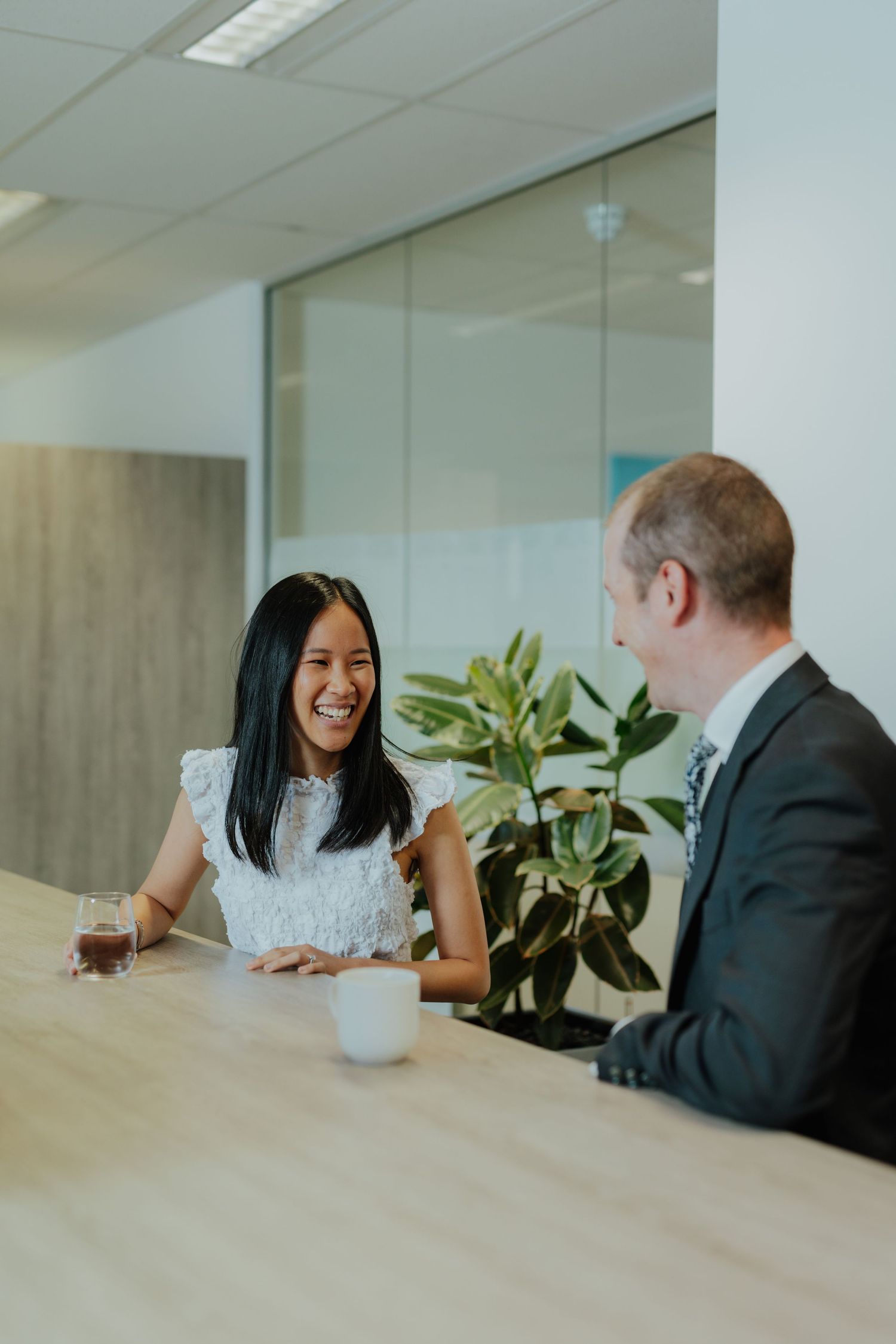 Young woman and businessman having a friendly meeting at a wooden table in a modern office.