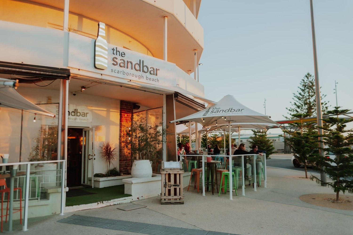 The Sandbar restaurant exterior with outdoor seating area and signage at twilight.