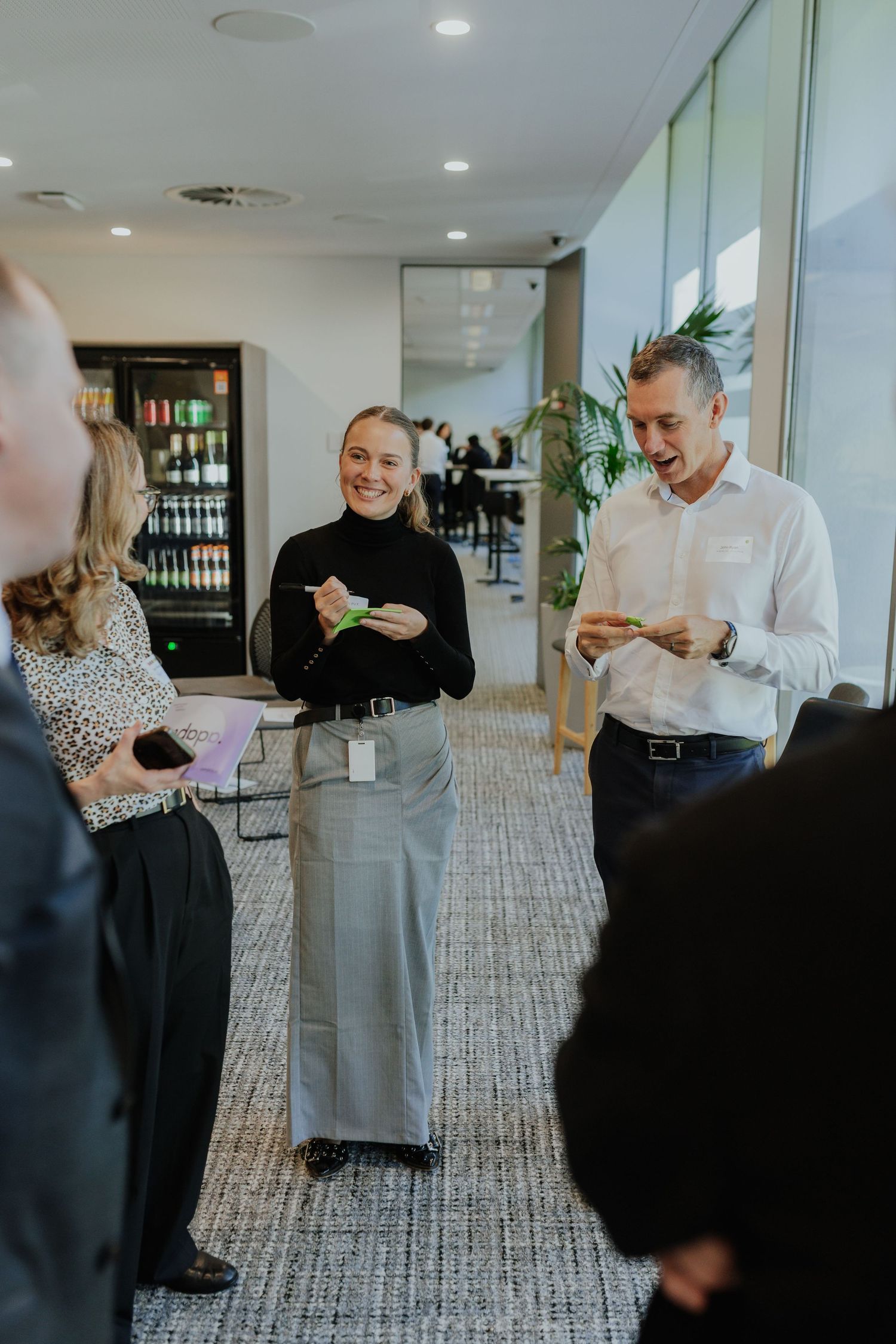 Business professionals networking and socializing in a modern corporate office breakout space.