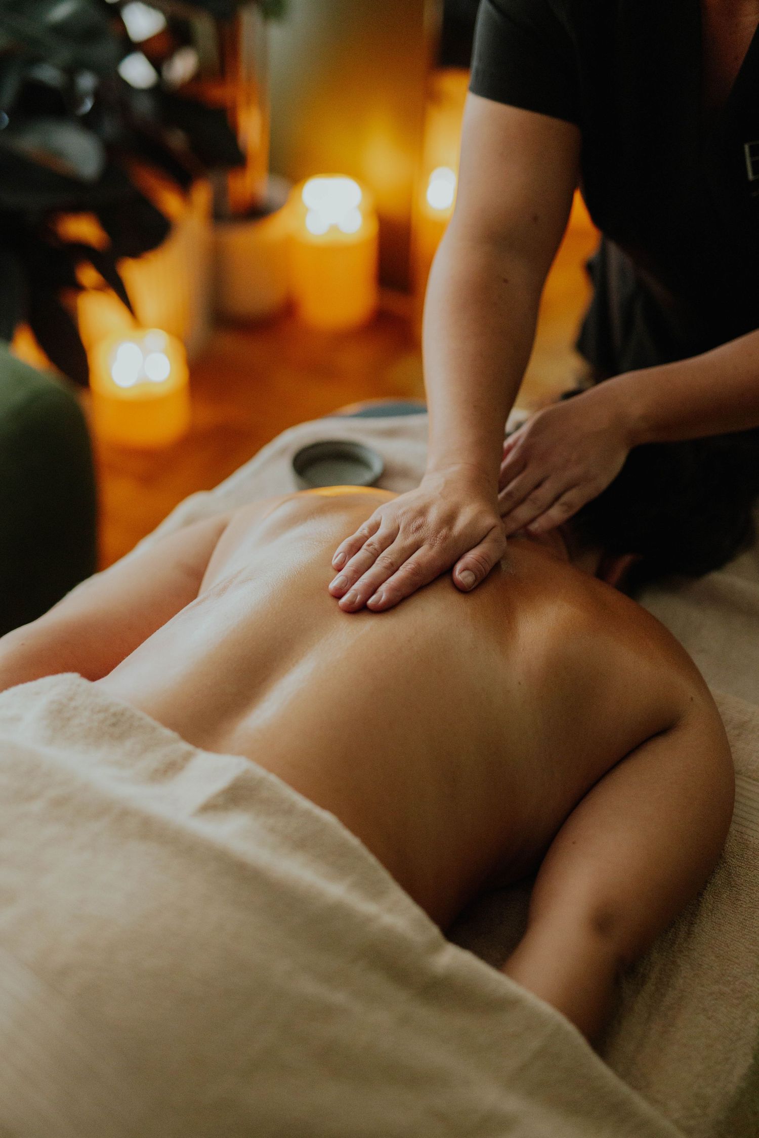 Massage therapist performing a back massage by candlelight in a relaxing spa setting.
