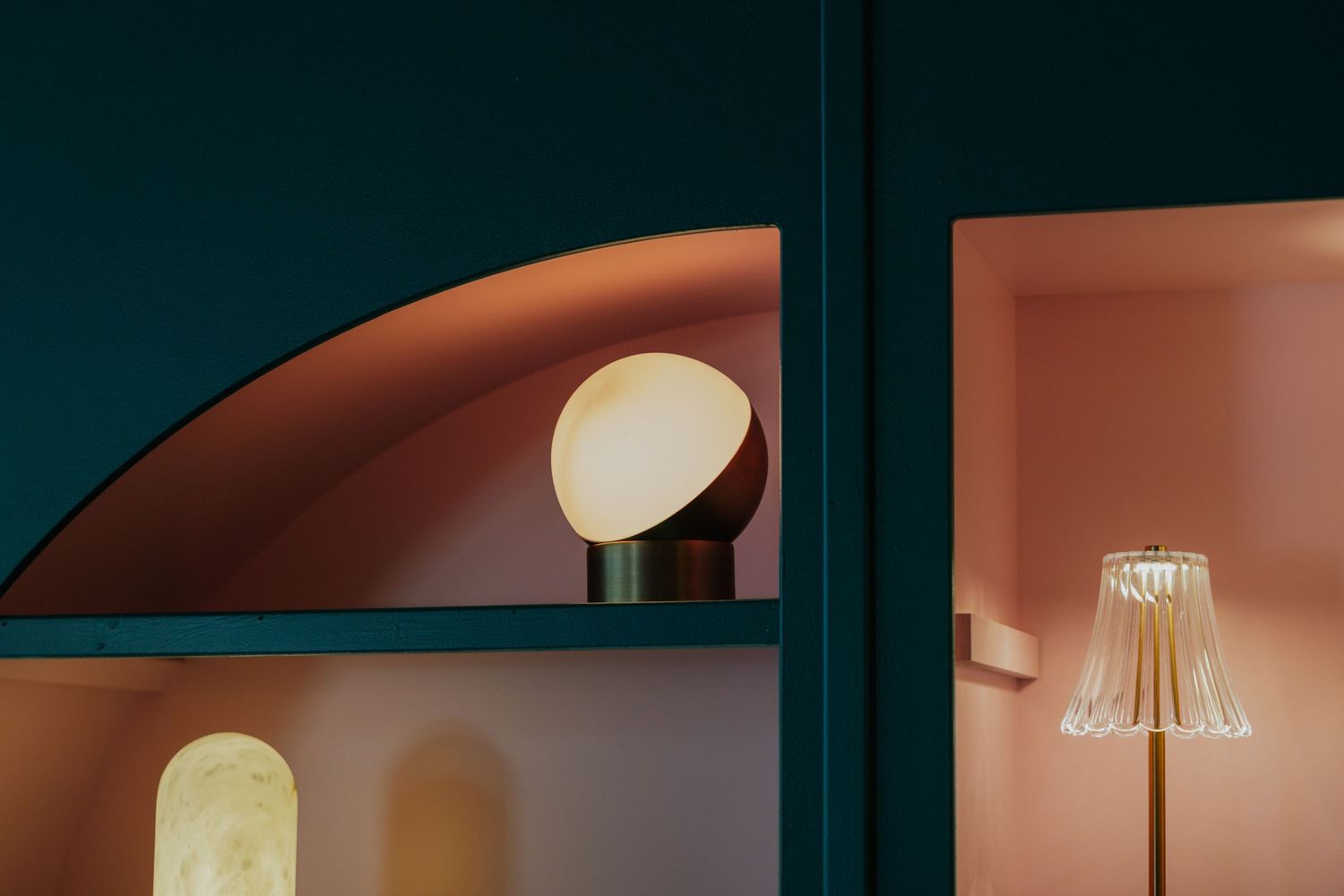Elegant table lamp display in pink and teal architectural nook with arched details.