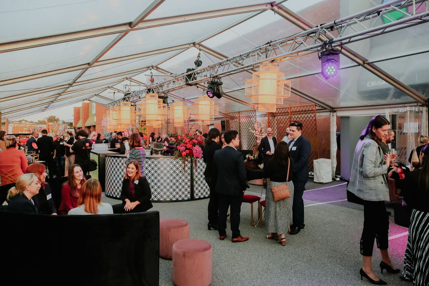 Elegantly decorated event marquee with guests mingling under warm ambient lighting.