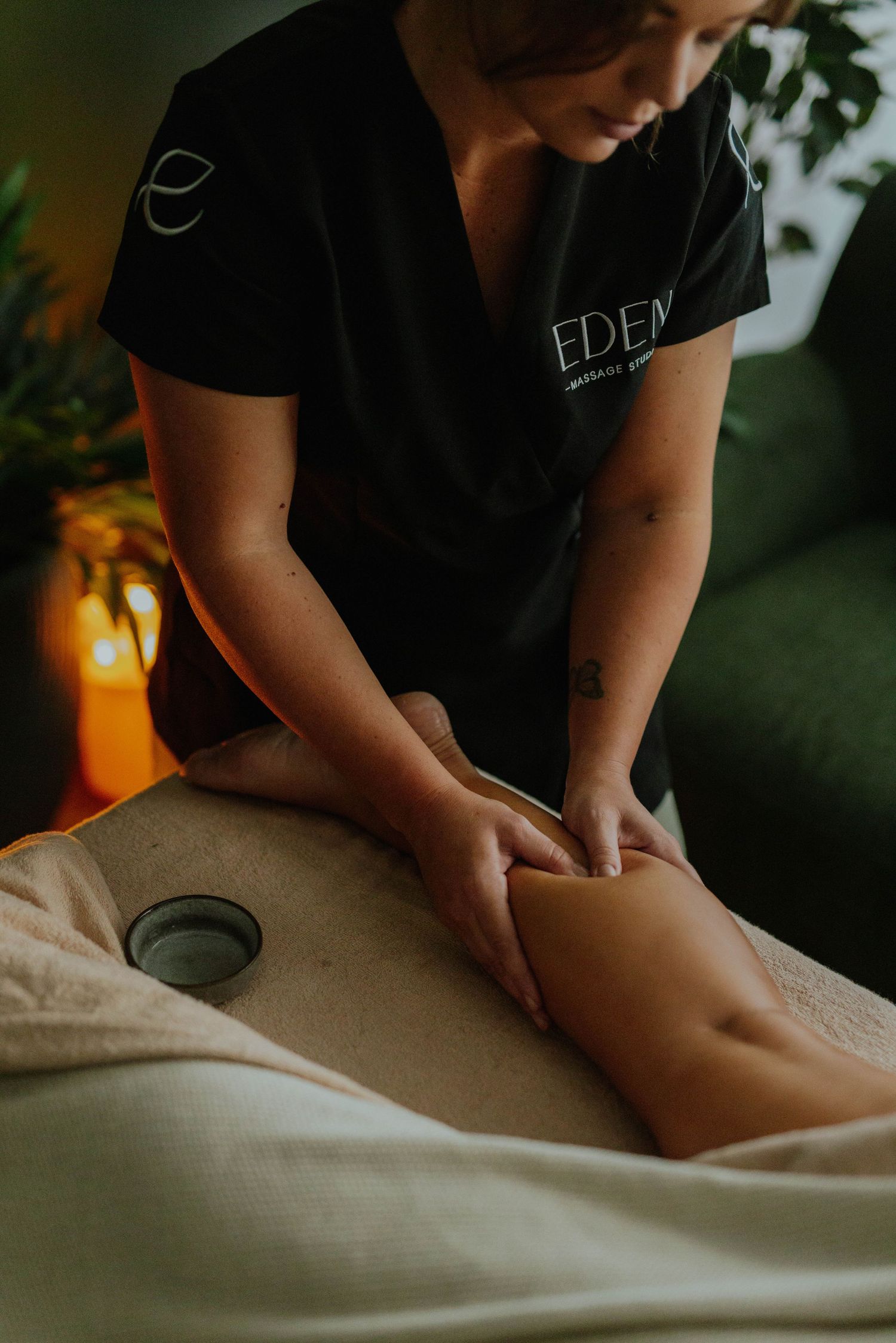 Eden Massage Studio therapist performing a professional leg massage on a client lying on a treatment table.