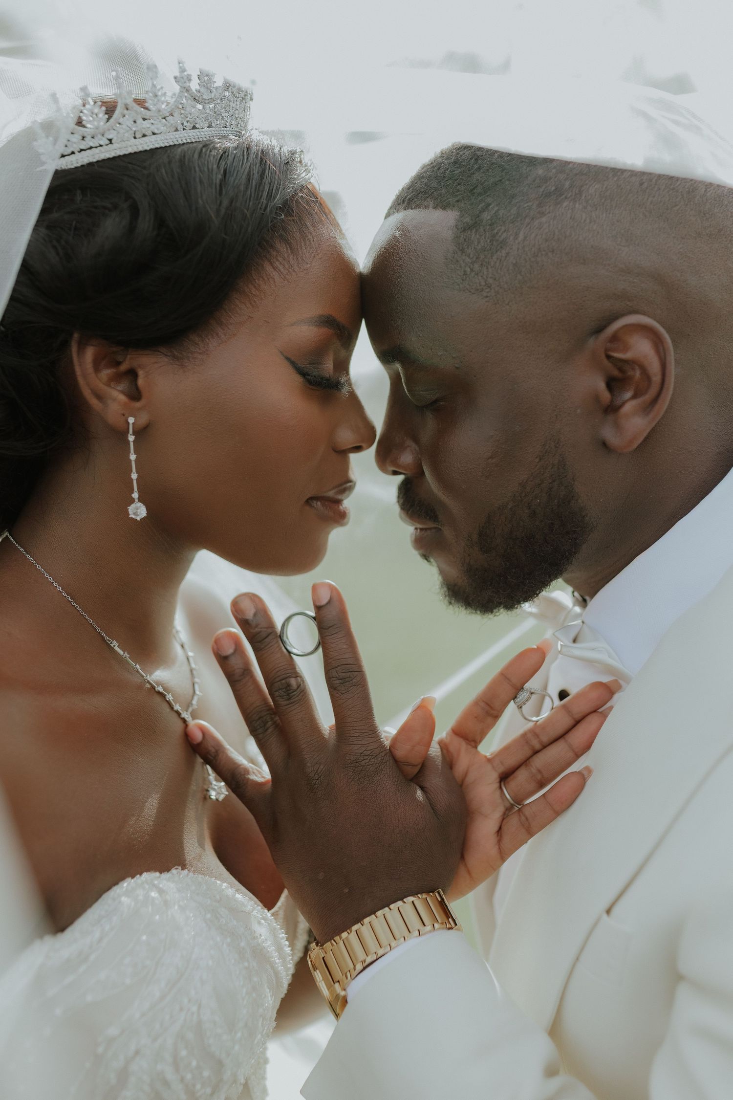 African American bride and groom touching foreheads tenderly, bride wearing diamond crown.