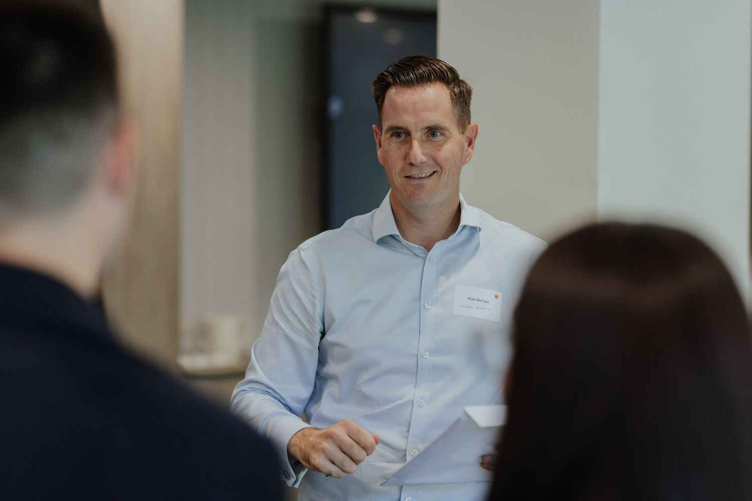 Professional man in light blue shirt engages in conversation at a corporate business event.