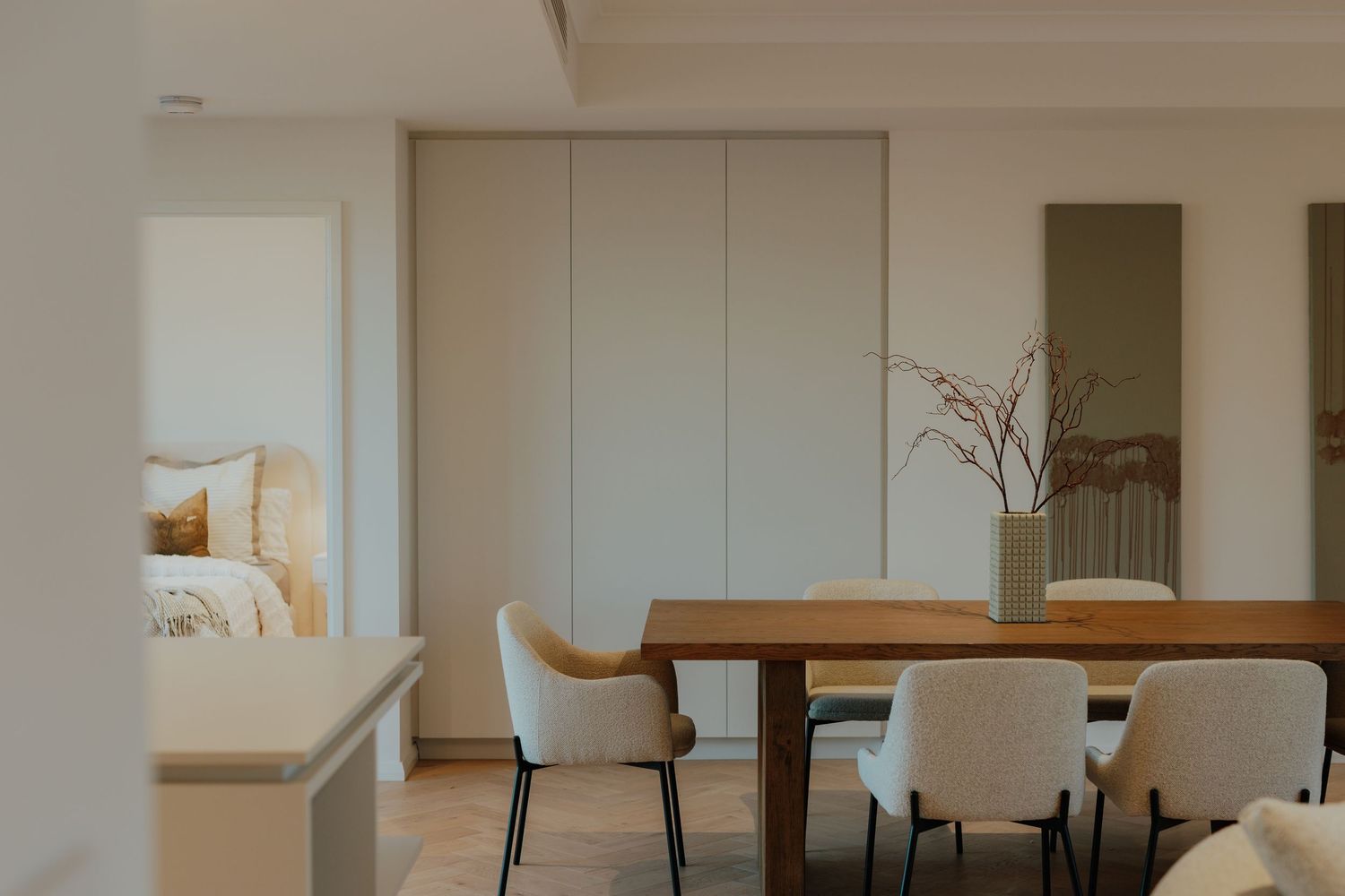 Modern minimalist dining room with wooden table, white chairs, and neutral decor.