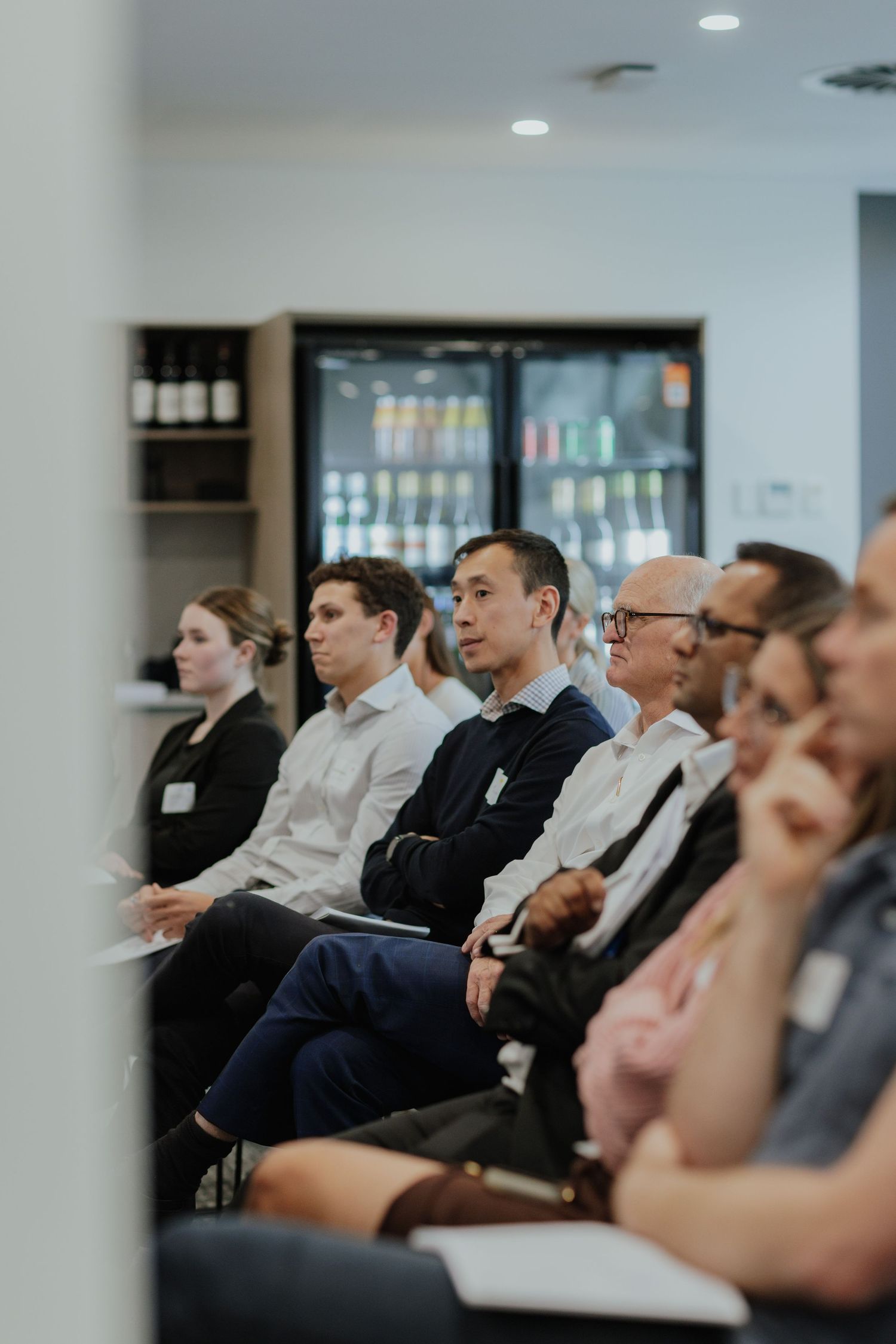 Diverse group of business professionals seated and attentively listening at an indoor corporate seminar event.