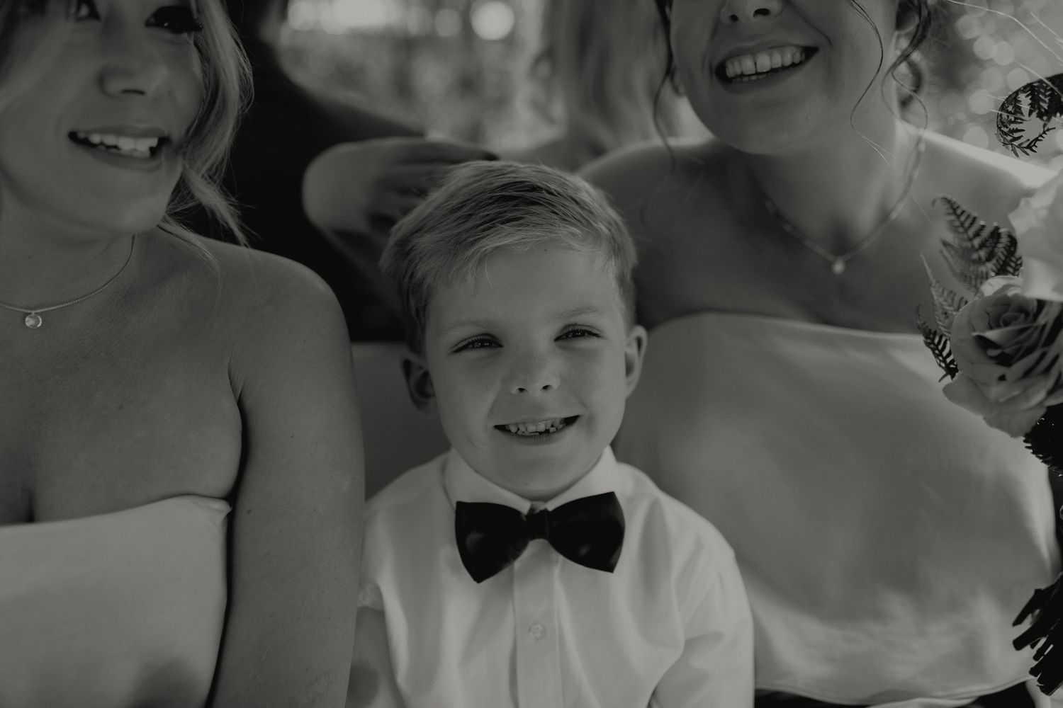 Black and white photo of boy in bow tie with two women.