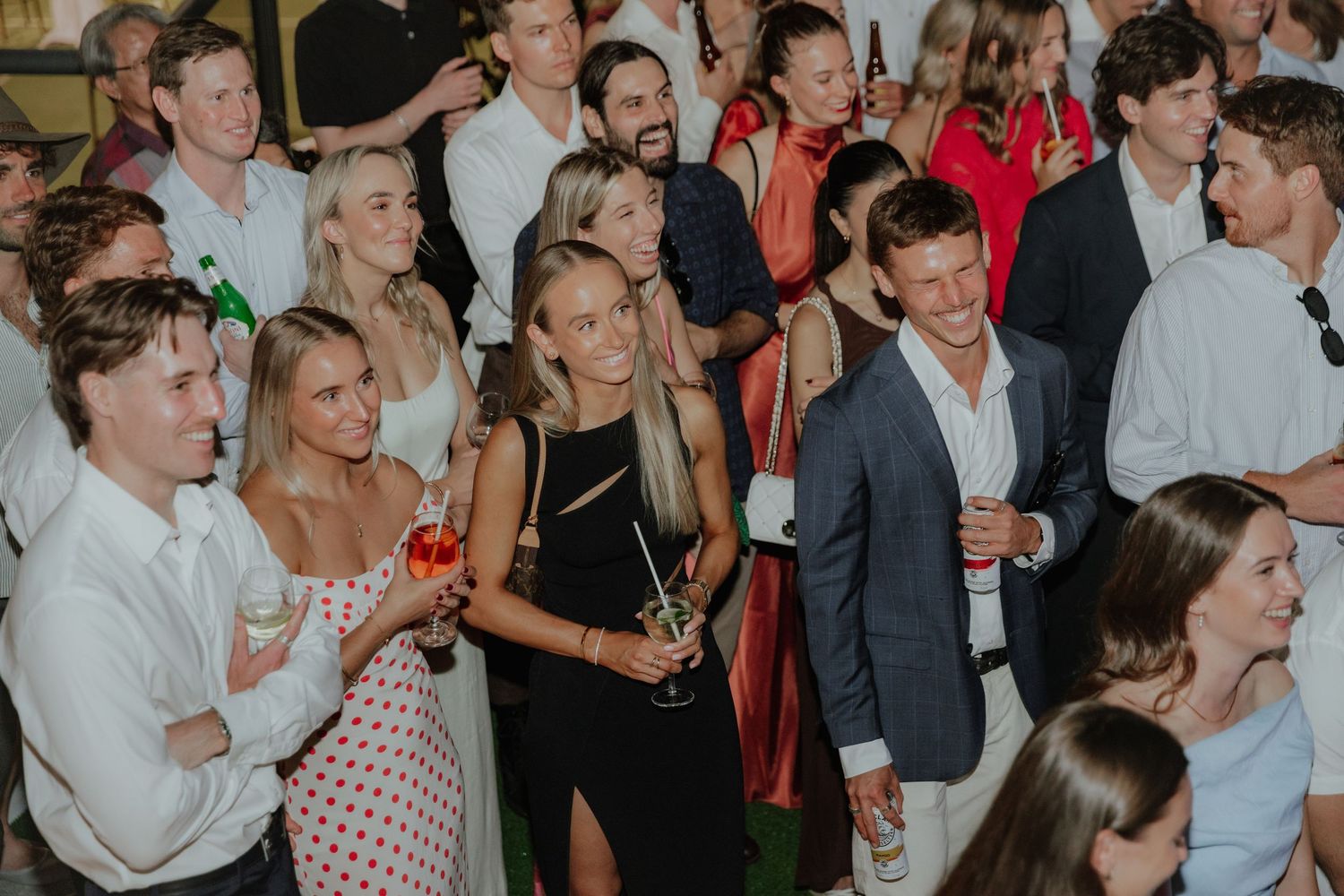 Guests socializing and smiling at a lively indoor wedding reception party celebration.